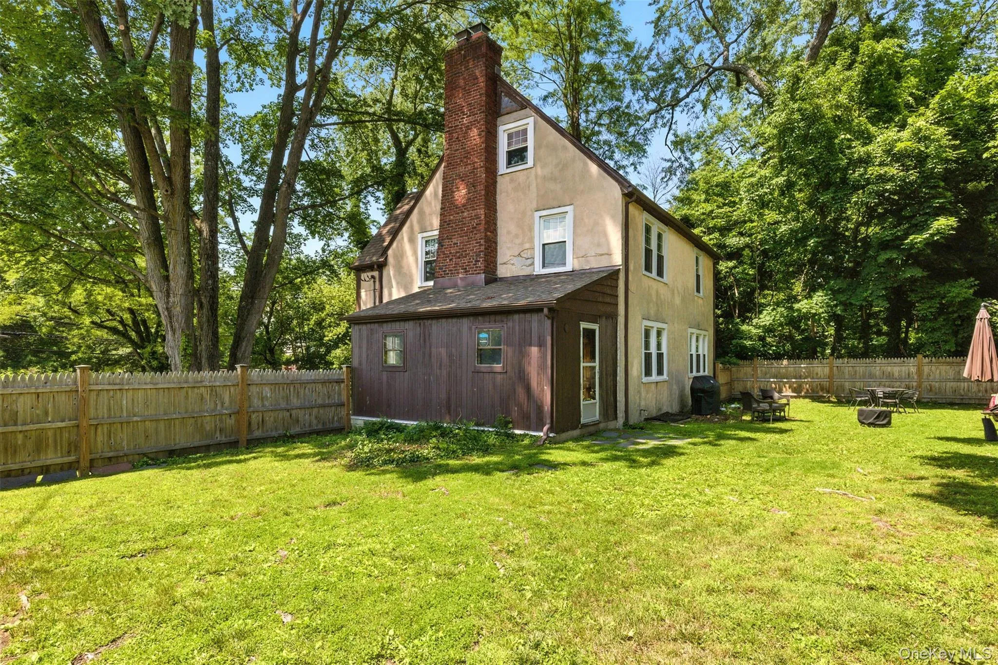 Back of property with a chimney, a fenced backyard, and stucco siding Back of property with a chimney, a fenced backyard, and stucco siding