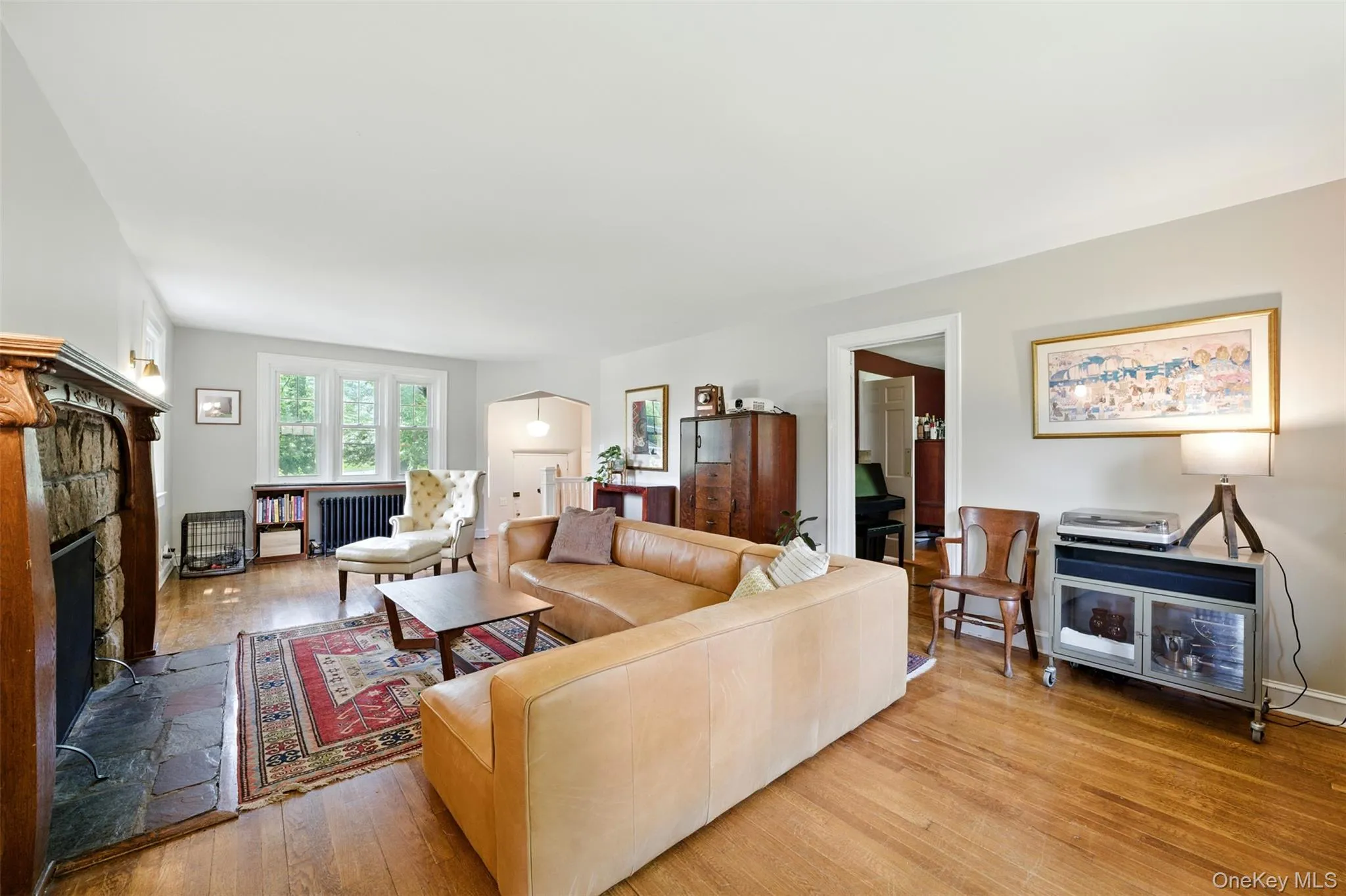 Living area with radiator heating unit, light wood finished floors, and a stone fireplace Living area with radiator heating unit, light wood finished floors, and a stone fireplace