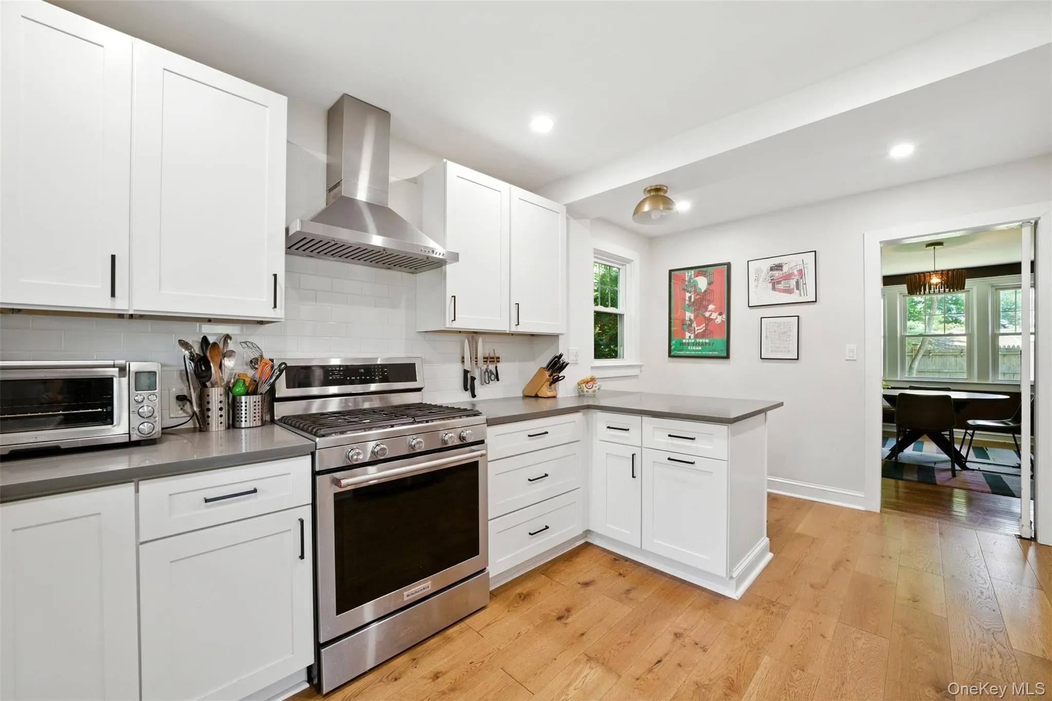 Kitchen with stainless steel gas range, wall chimney exhaust hood, dark countertops, decorative backsplash, and recessed lighting Kitchen with stainless steel gas range, wall chimney exhaust hood, dark countertops, decorative backsplash, and recessed lighting