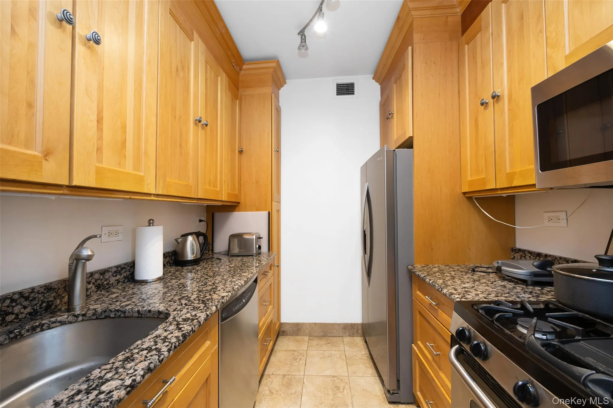 Kitchen with a sink, dark stone counters, stainless steel appliances, baseboards, and visible vents Kitchen with a sink, dark stone counters, stainless steel appliances, baseboards, and visible vents