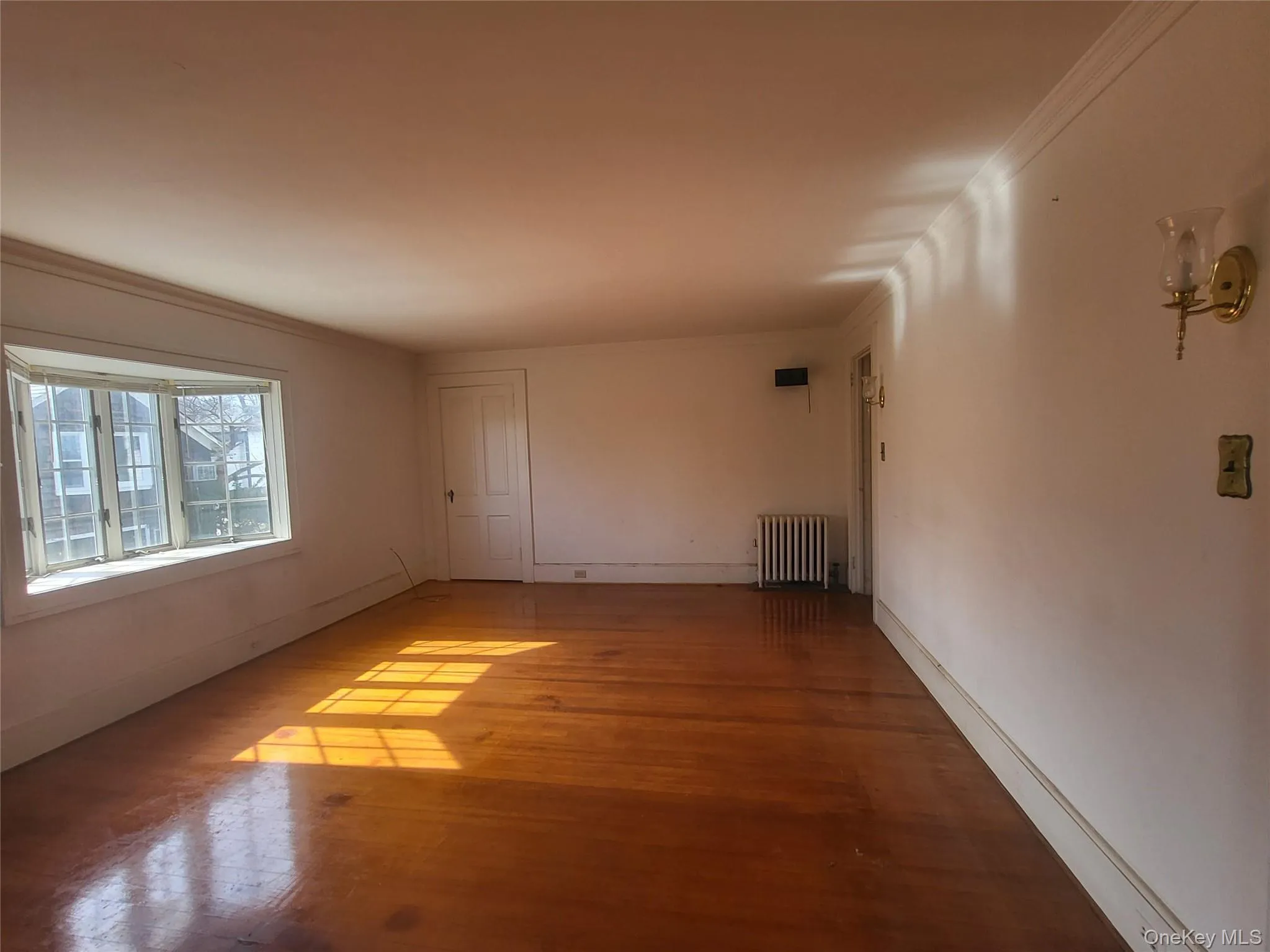 Living room with hardwood floors , sconces, and bay window Living room with hardwood floors , sconces, and bay window
