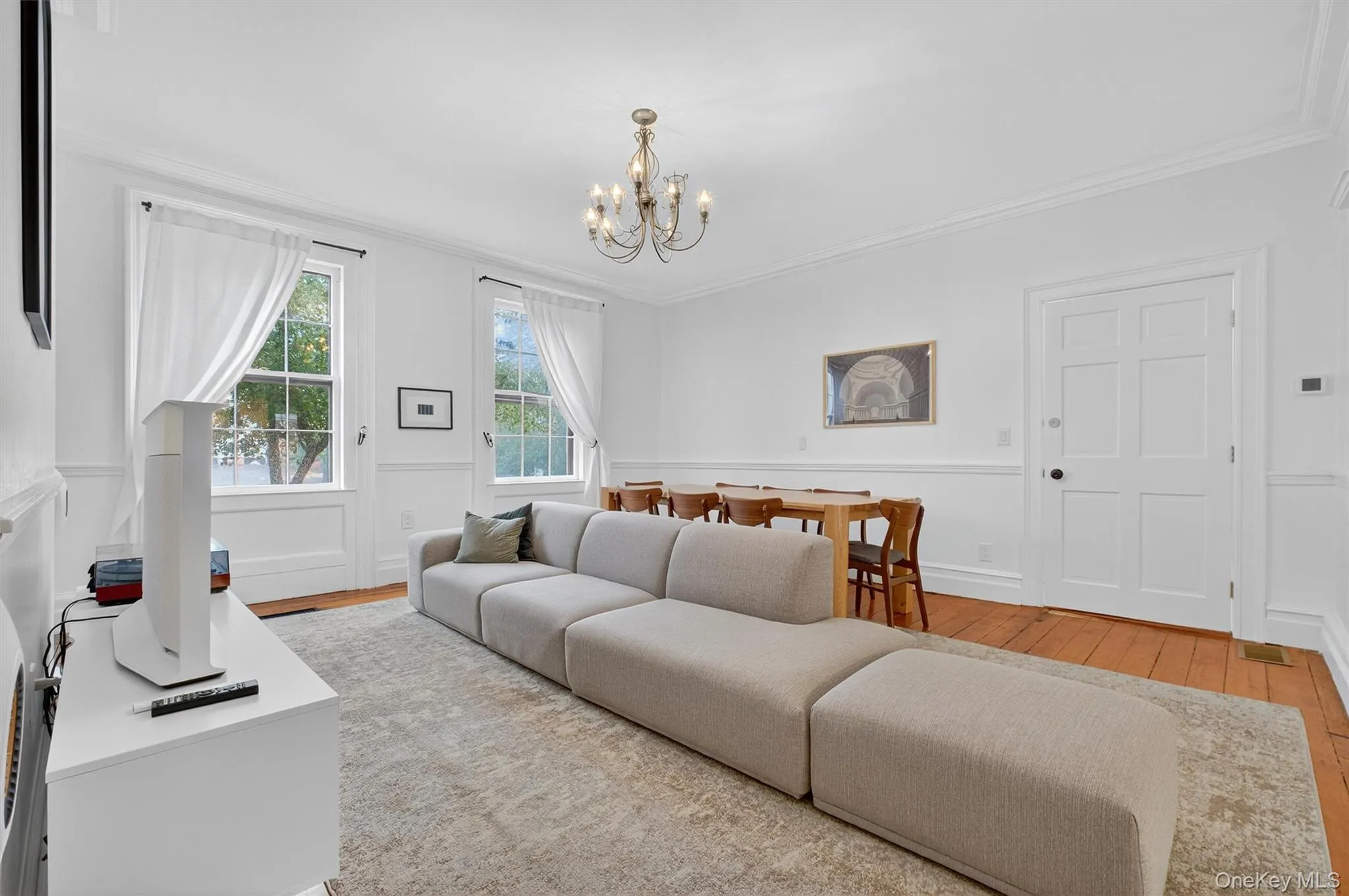 Living room featuring hardwood / wood-style flooring, ornamental molding, and a chandelier Living room featuring hardwood / wood-style flooring, ornamental molding, and a chandelier