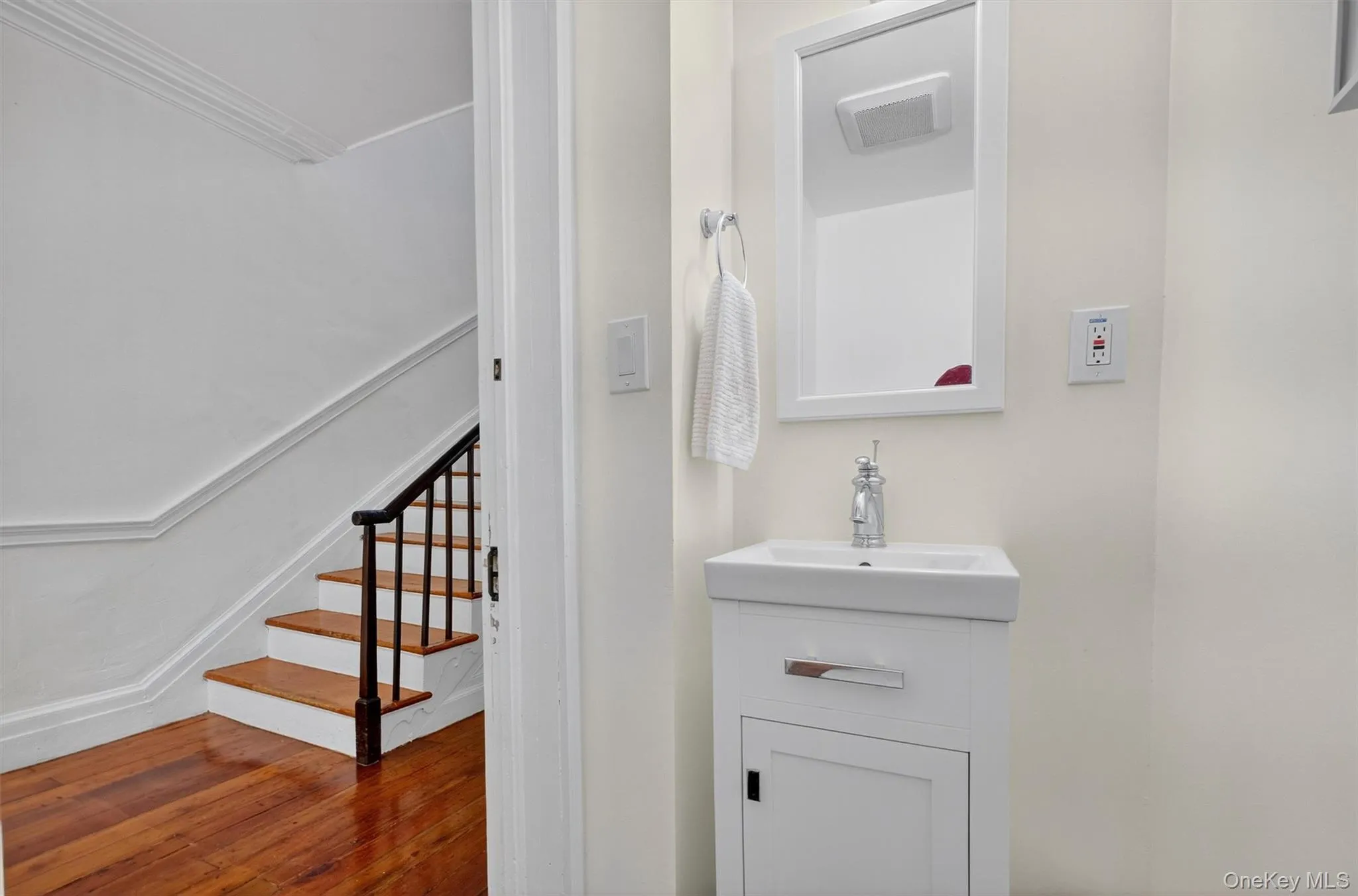 Bathroom with vanity, wood finished floors, and ornamental molding Bathroom with vanity, wood finished floors, and ornamental molding