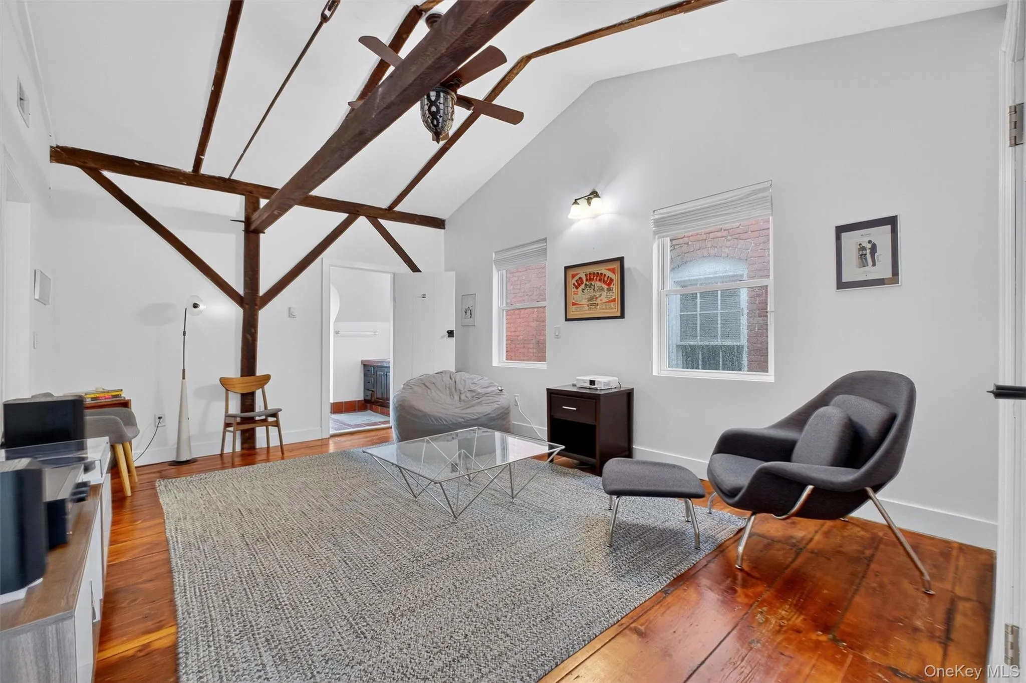 Sitting room featuring hardwood / wood-style flooring, high vaulted ceiling, beam ceiling, and ceiling fan Sitting room featuring hardwood / wood-style flooring, high vaulted ceiling, beam ceiling, and ceiling fan