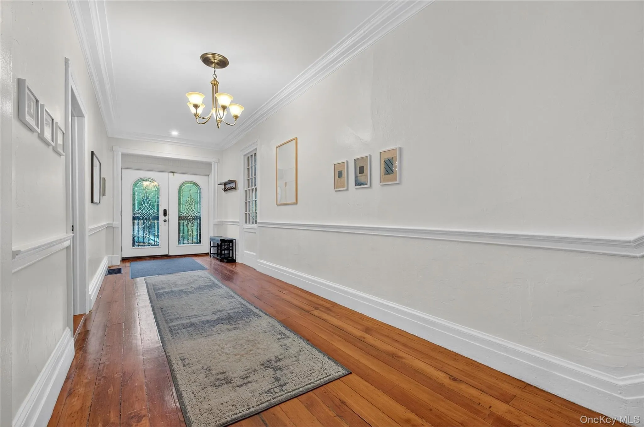 Doorway to outside featuring hardwood / wood-style flooring, crown molding, a chandelier, and french doors Doorway to outside featuring hardwood / wood-style flooring, crown molding, a chandelier, and french doors