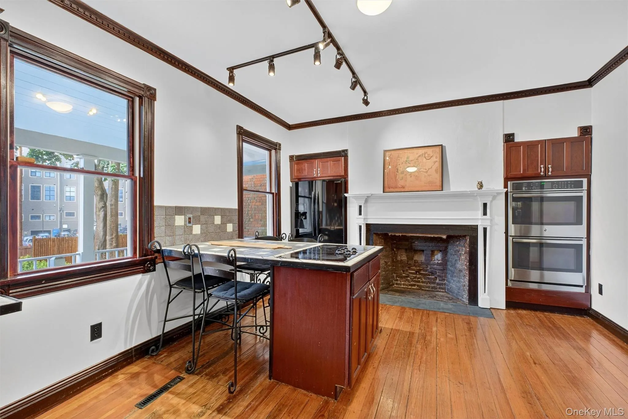 Kitchen with crown molding, rail lighting, black appliances, a peninsula, and a breakfast bar Kitchen with crown molding, rail lighting, black appliances, a peninsula, and a breakfast bar