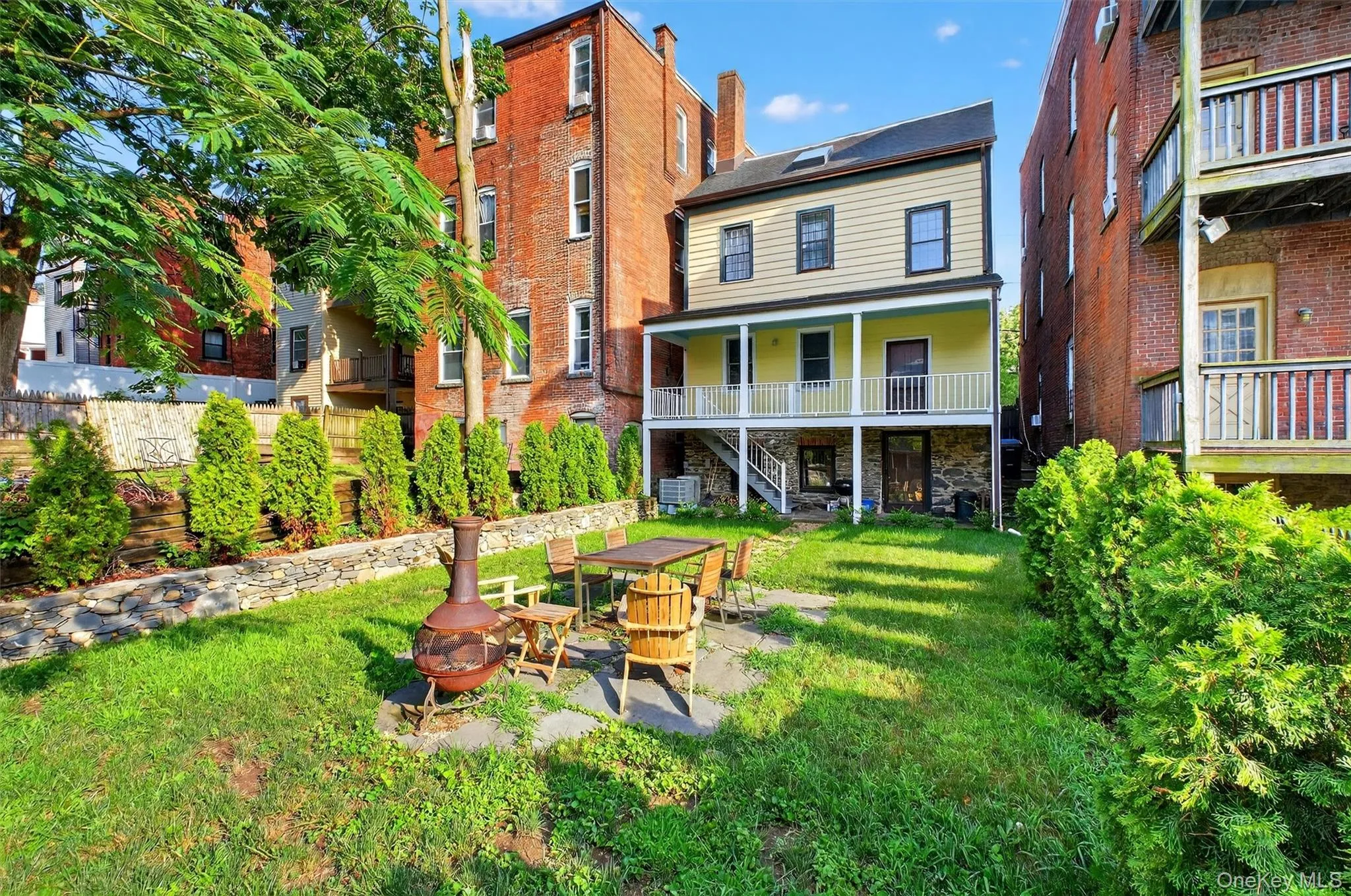 Back of property featuring a fire pit, stairs, a yard, and a patio Back of property featuring a fire pit, stairs, a yard, and a patio