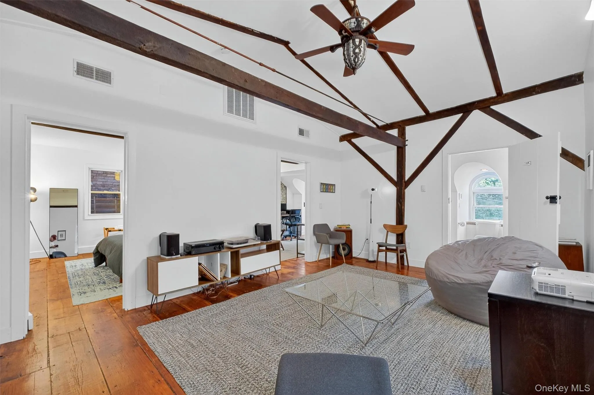 Living area featuring hardwood / wood-style floors, ceiling fan, high vaulted ceiling, and beamed ceiling Living area featuring hardwood / wood-style floors, ceiling fan, high vaulted ceiling, and beamed ceiling