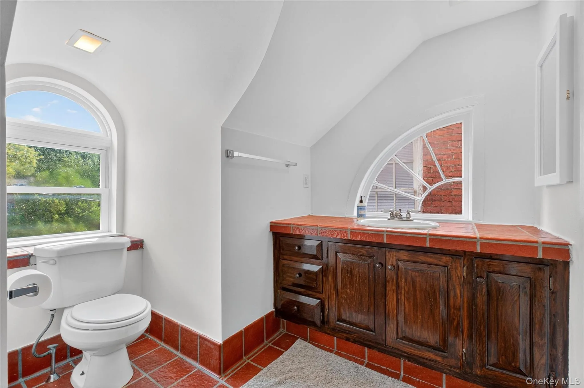 Half bath with tile patterned flooring, vaulted ceiling, and vanity Half bath with tile patterned flooring, vaulted ceiling, and vanity