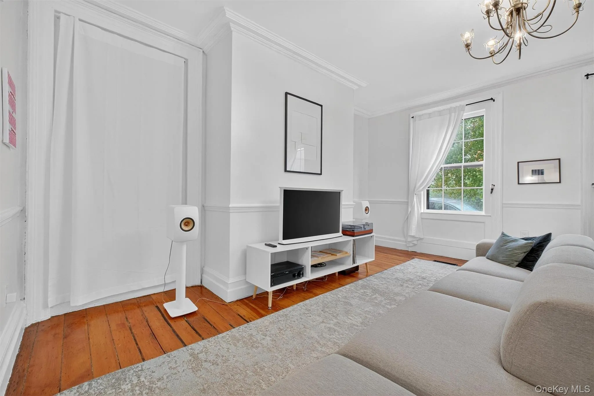 Living area featuring hardwood / wood-style flooring, ornamental molding, and a chandelier Living area featuring hardwood / wood-style flooring, ornamental molding, and a chandelier