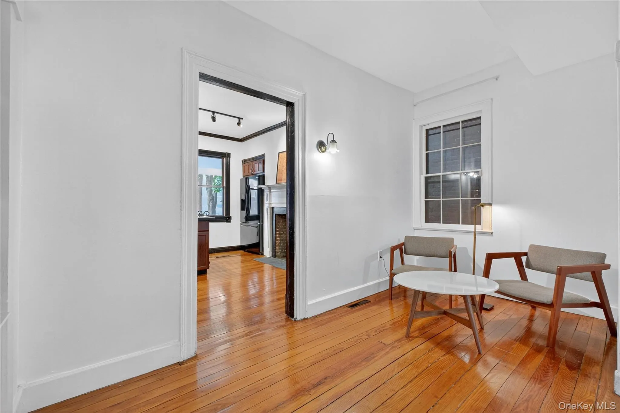 Living area with track lighting, light wood-style flooring, crown molding, and a fireplace with flush hearth Living area with track lighting, light wood-style flooring, crown molding, and a fireplace with flush hearth