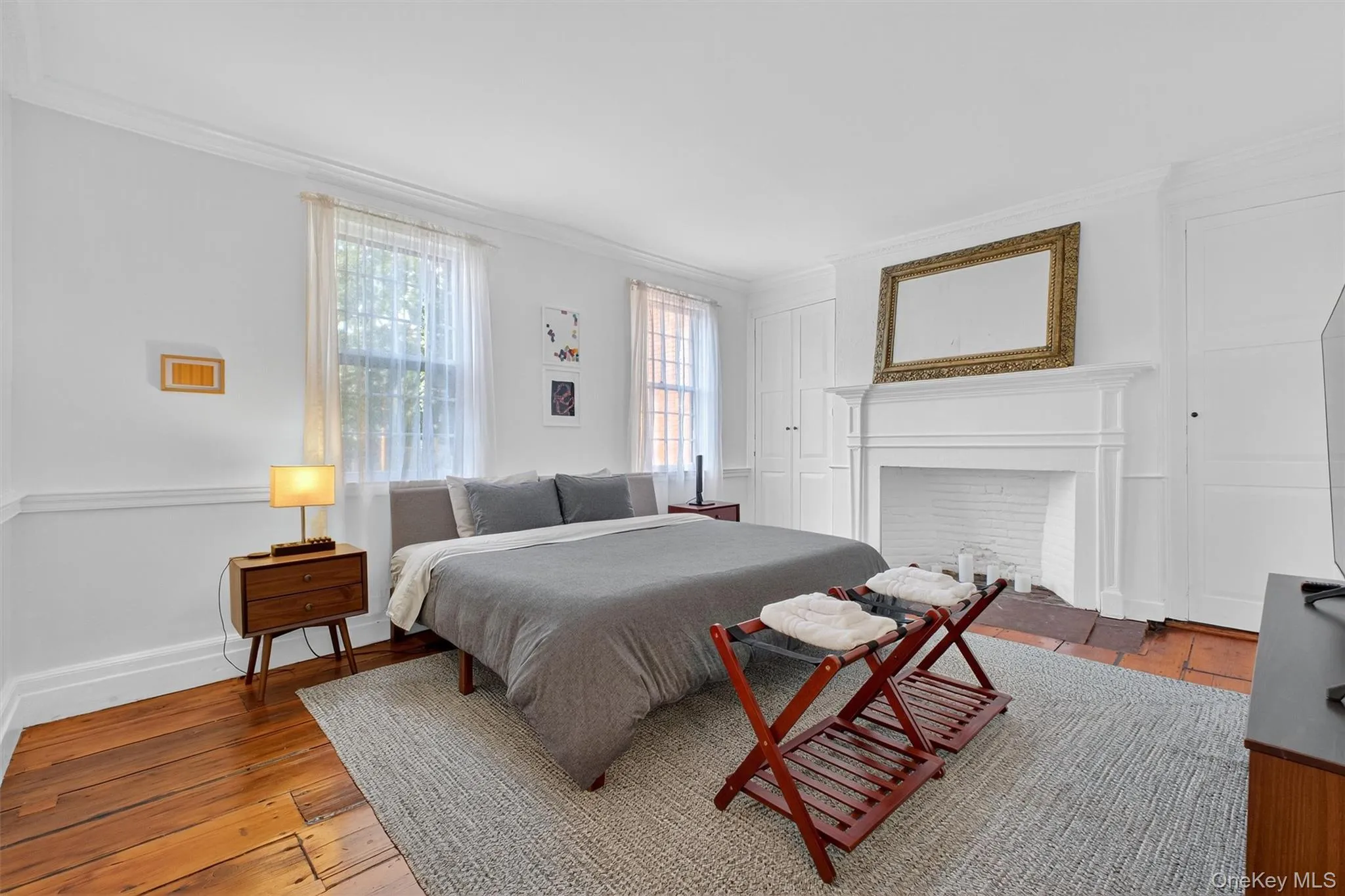 Bedroom with crown molding, light wood finished floors, and a fireplace Bedroom with crown molding, light wood finished floors, and a fireplace