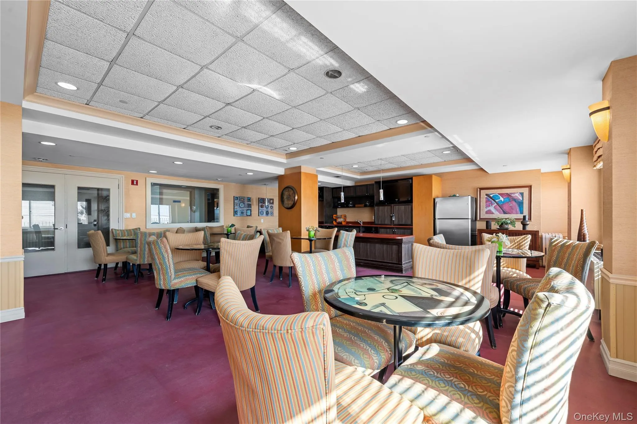 Common area featuring multiple seating arrangements, a full kitchen with stainless steel appliances, recessed lighting, and wall sconces Common area featuring multiple seating arrangements, a full kitchen with stainless steel appliances, recessed lighting, and wall sconces