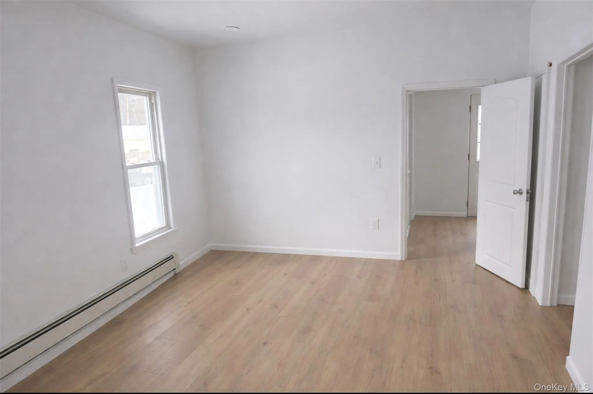Unfurnished room featuring a baseboard radiator and light wood-style flooring Unfurnished room featuring a baseboard radiator and light wood-style flooring
