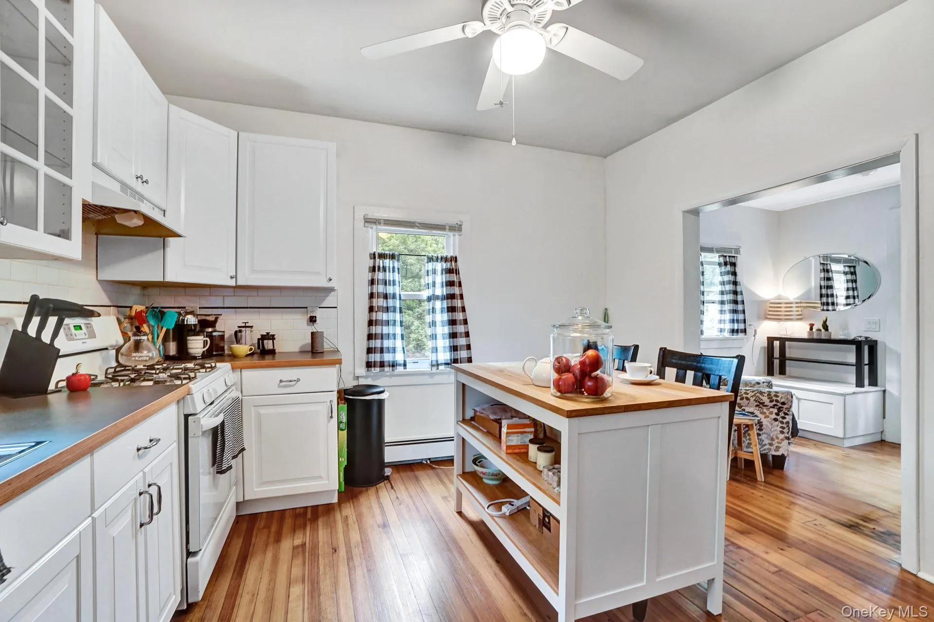 Kitchen with white cabinets, a baseboard heating unit, butcher block counters, decorative backsplash, and white gas range oven Kitchen with white cabinets, a baseboard heating unit, butcher block counters, decorative backsplash, and white gas range oven