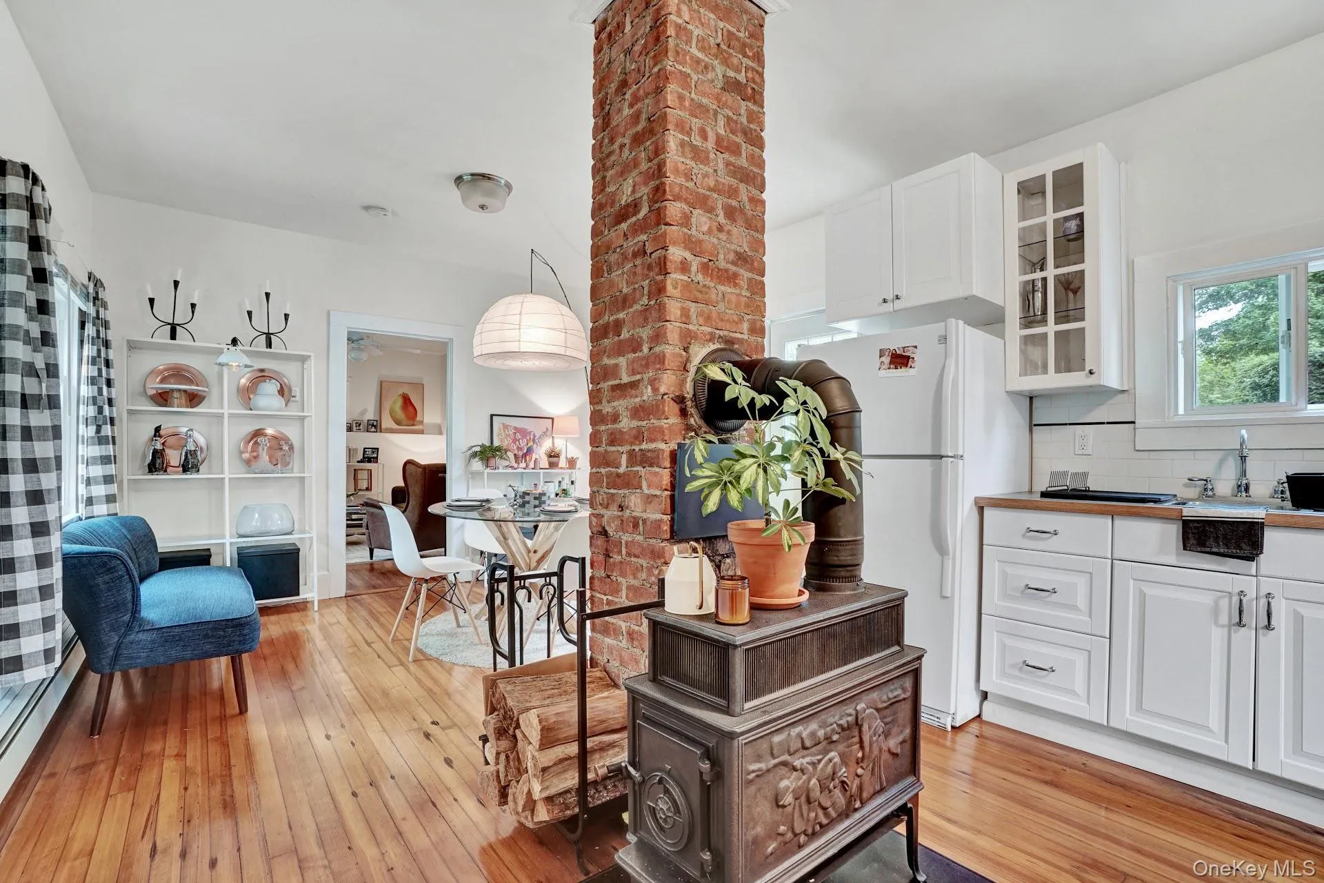 Kitchen with white cabinets, freestanding refrigerator, light wood-style flooring, and glass insert cabinets Kitchen with white cabinets, freestanding refrigerator, light wood-style flooring, and glass insert cabinets