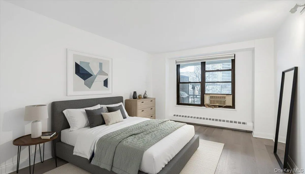 Bedroom featuring baseboard heating and wood finished floors Bedroom featuring baseboard heating and wood finished floors