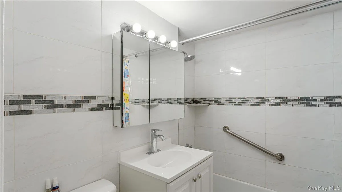 Bathroom featuring vanity, tiled shower, and tile walls Bathroom featuring vanity, tiled shower, and tile walls