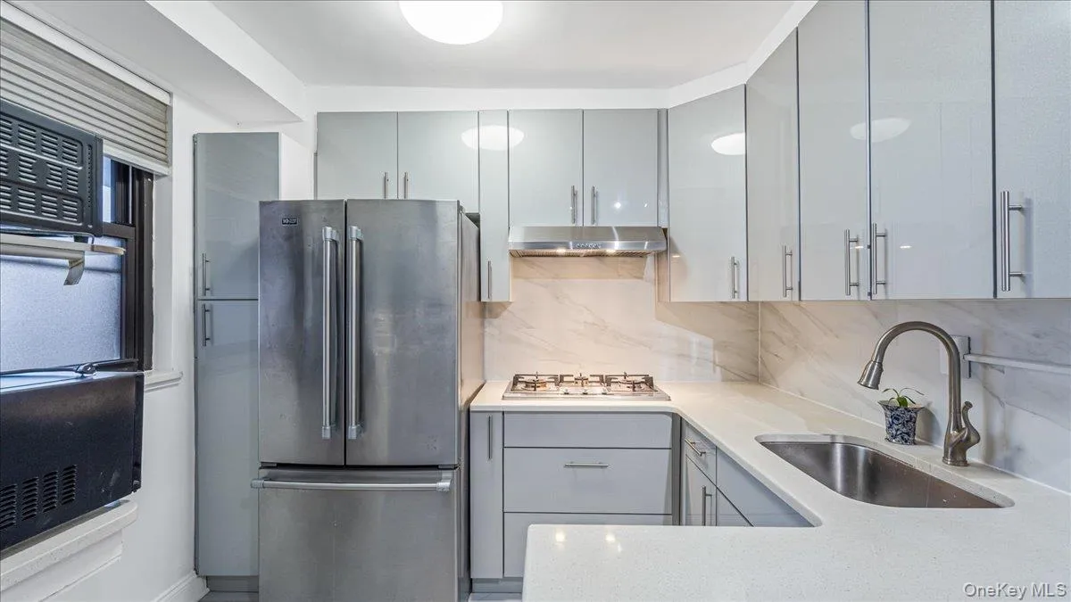 Kitchen featuring gray cabinetry, stainless steel appliances, light stone counters, and backsplash Kitchen featuring gray cabinetry, stainless steel appliances, light stone counters, and backsplash