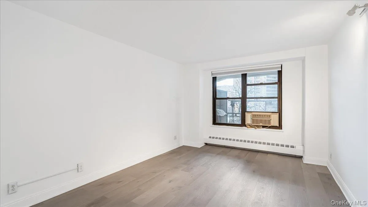Empty room featuring light wood finished floors and a baseboard heating unit Empty room featuring light wood finished floors and a baseboard heating unit