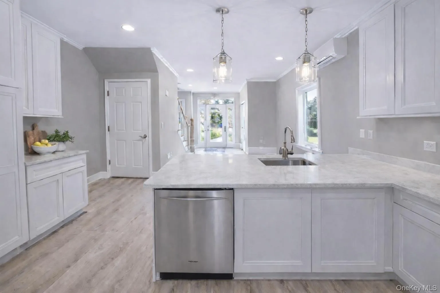 Modern kitchen featuring white shaker cabinetry, light-toned countertops, and wood-finish flooring Modern kitchen featuring white shaker cabinetry, light-toned countertops, and wood-finish flooring