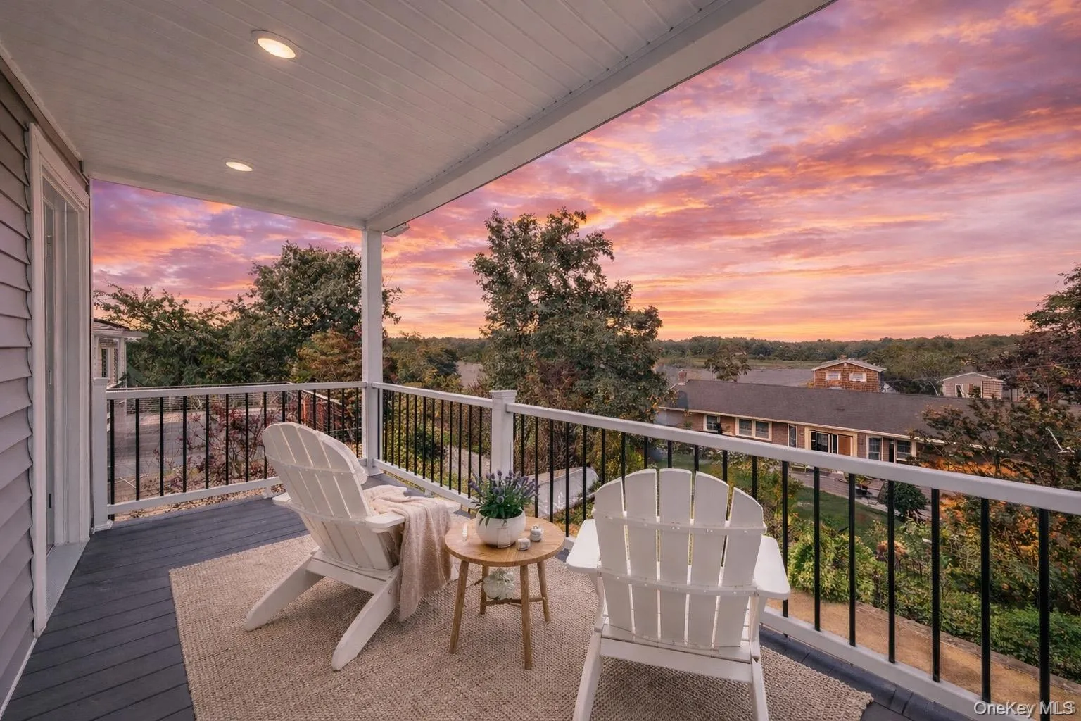 Covered balcony featuring recessed lighting, a dark gray floor, and a white balustrade with black spindles Covered balcony featuring recessed lighting, a dark gray floor, and a white balustrade with black spindles