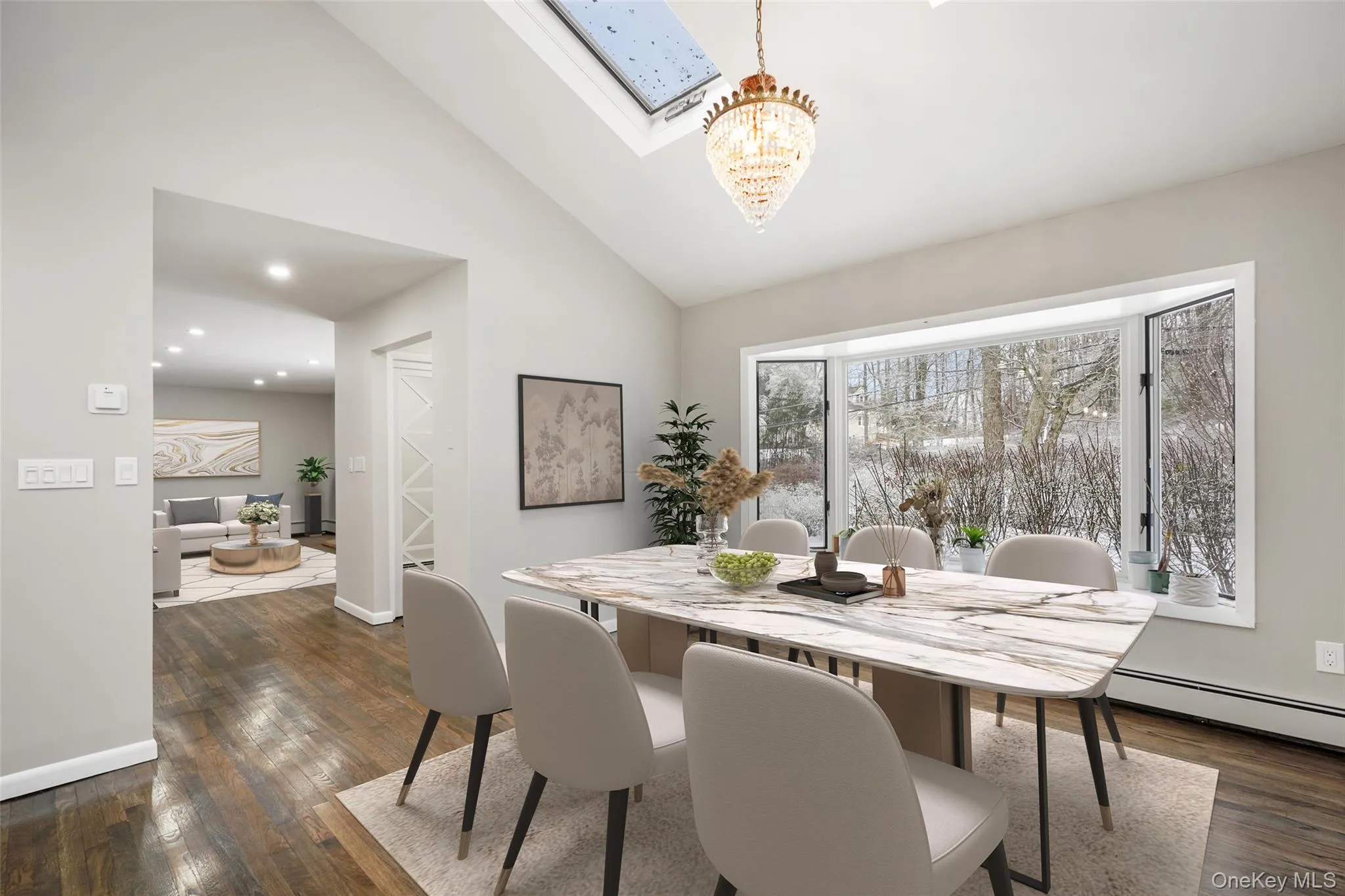 Dining space with dark wood finished floors, a skylight, vaulted ceiling, suspended lighting, and baseboard heating. *Virtually Staged* Dining space with dark wood finished floors, a skylight, vaulted ceiling, suspended lighting, and baseboard heating. *Virtually Staged*