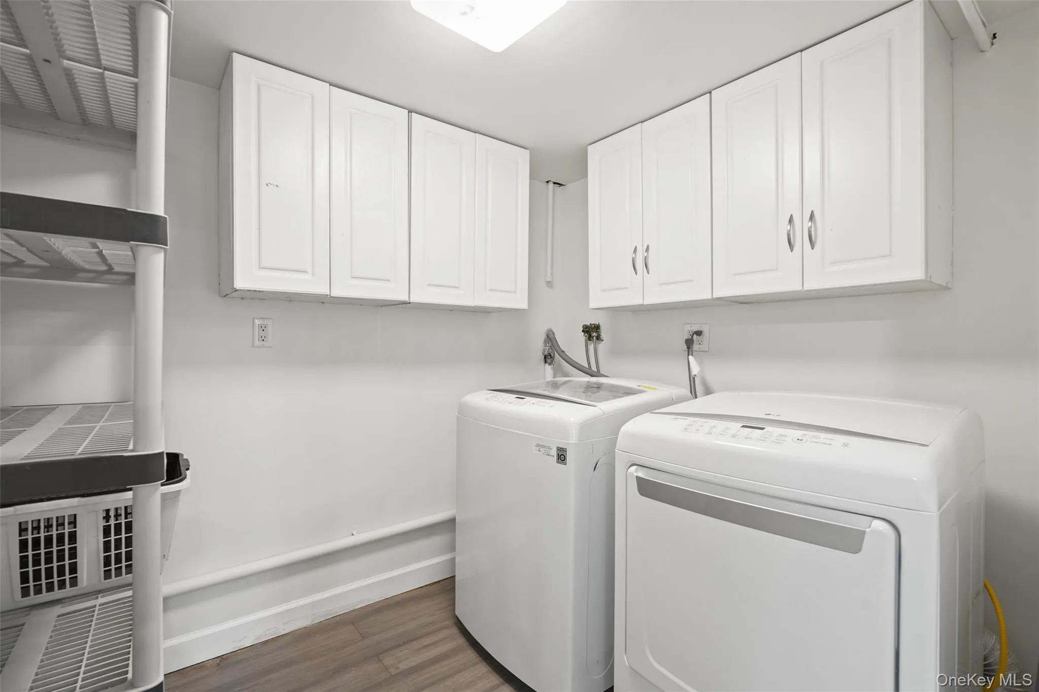 Laundry room featuring dark wood-type flooring, washing machine and clothes dryer, and cabinet space Laundry room featuring dark wood-type flooring, washing machine and clothes dryer, and cabinet space