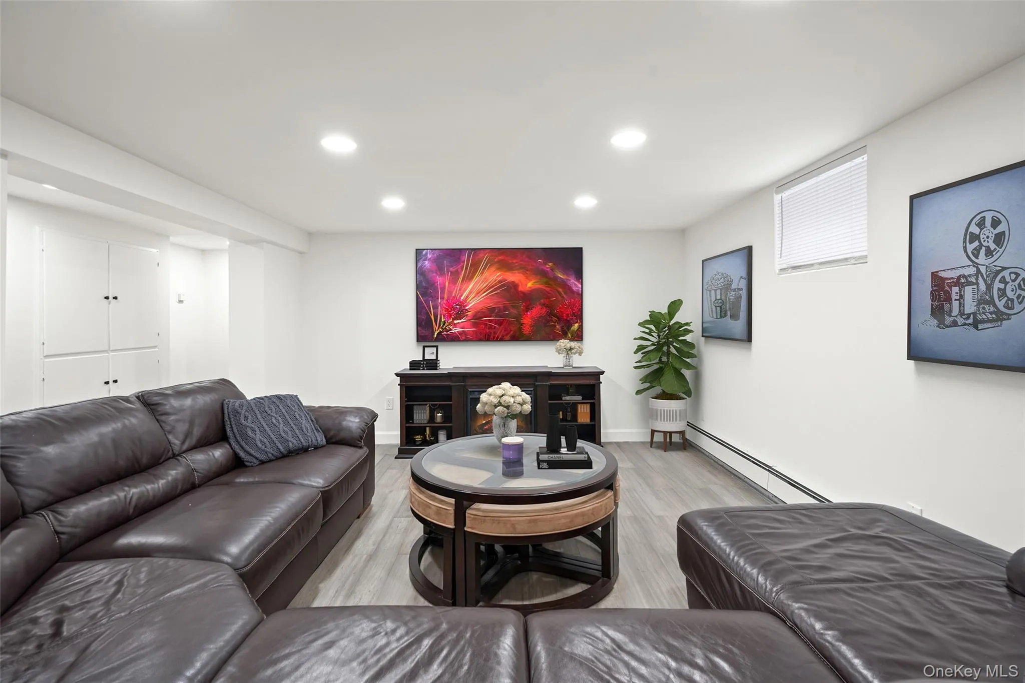 Living area with a baseboard radiator, light wood-style flooring, and recessed lighting. *Virtually Staged* Living area with a baseboard radiator, light wood-style flooring, and recessed lighting. *Virtually Staged*