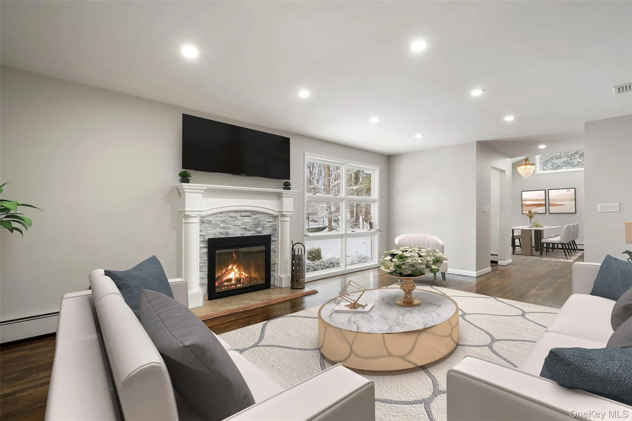 Living area featuring dark wood-style floors, recessed lighting, a stone fireplace, and a baseboard heating unit. *Virtually Staged* Living area featuring dark wood-style floors, recessed lighting, a stone fireplace, and a baseboard heating unit. *Virtually Staged*