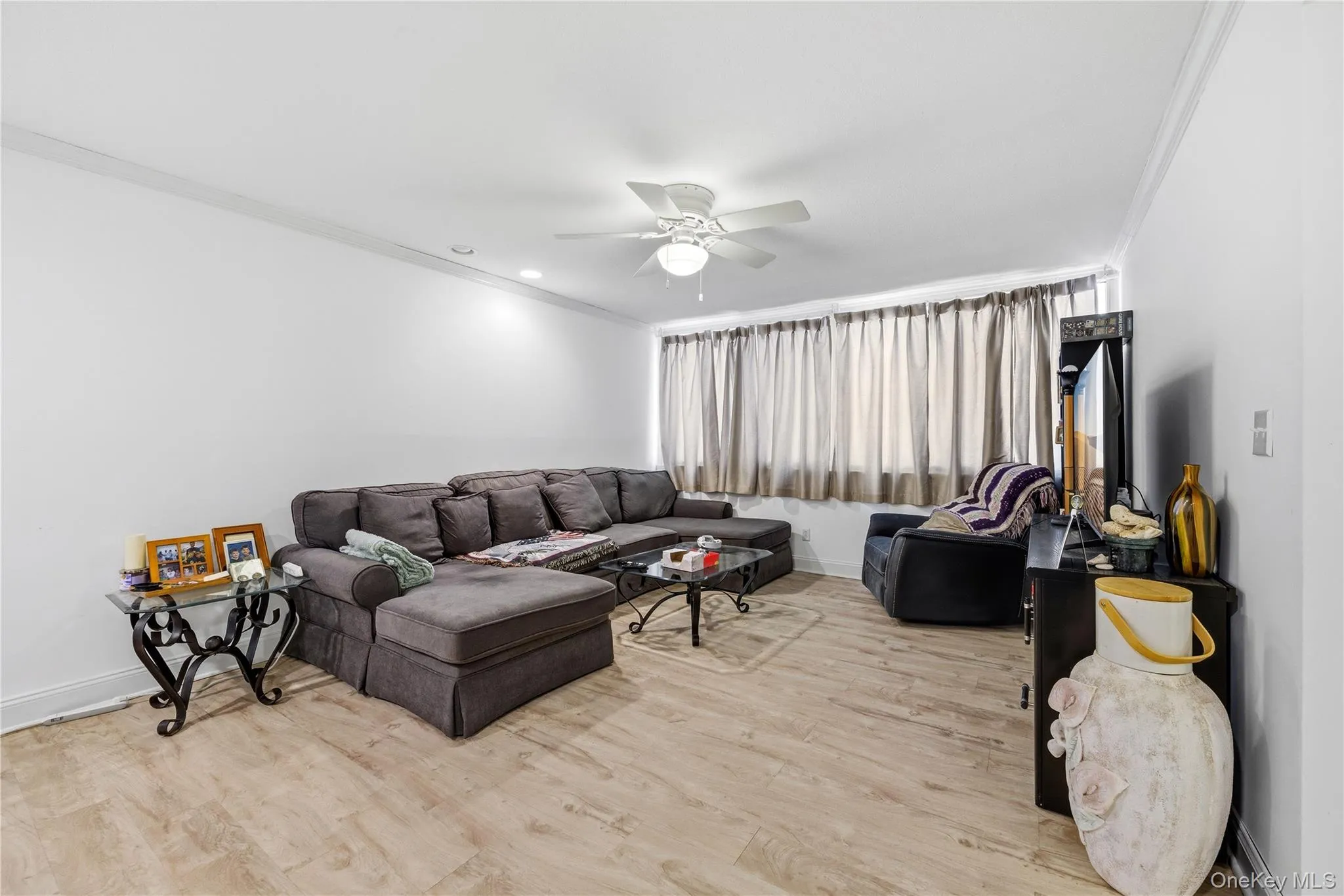 Living room with ornamental molding, light wood-style flooring, a ceiling fan, and recessed lighting Living room with ornamental molding, light wood-style flooring, a ceiling fan, and recessed lighting
