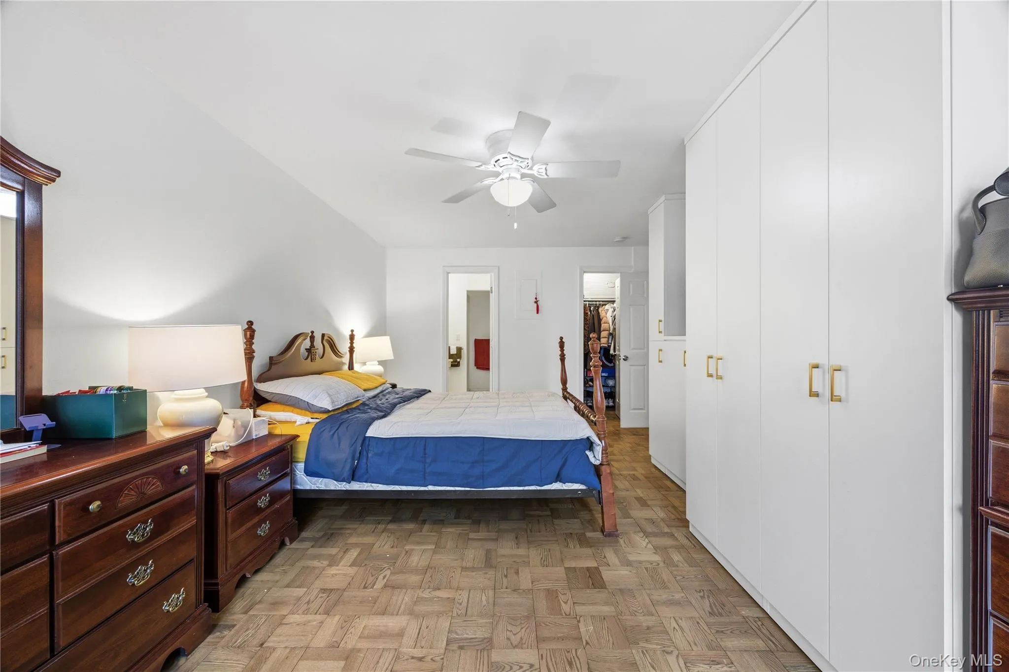 Bedroom featuring parquet flooring, a walk in closet, and a ceiling fan Bedroom featuring parquet flooring, a walk in closet, and a ceiling fan