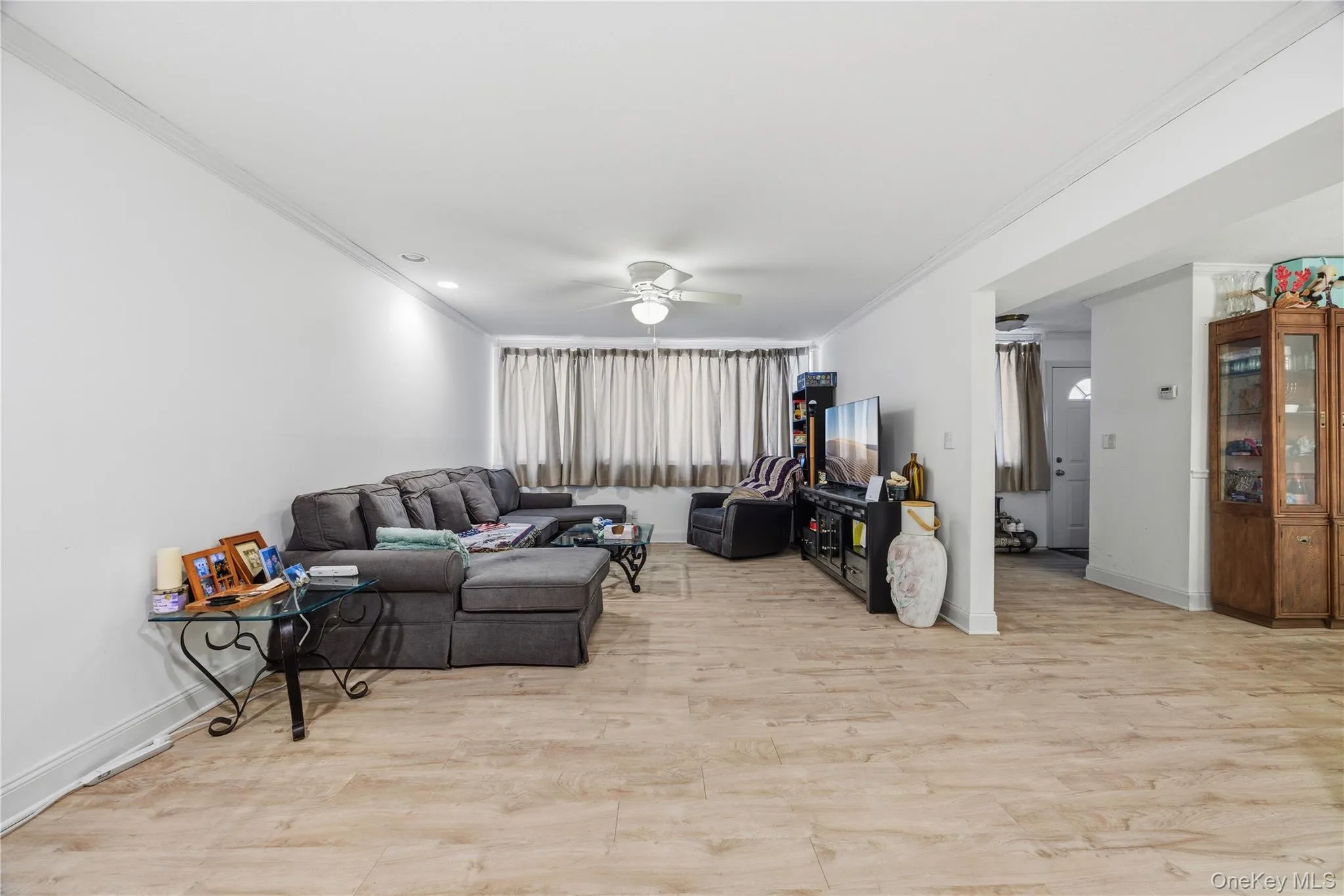 Living room with light wood-style floors, crown molding, and ceiling fan Living room with light wood-style floors, crown molding, and ceiling fan