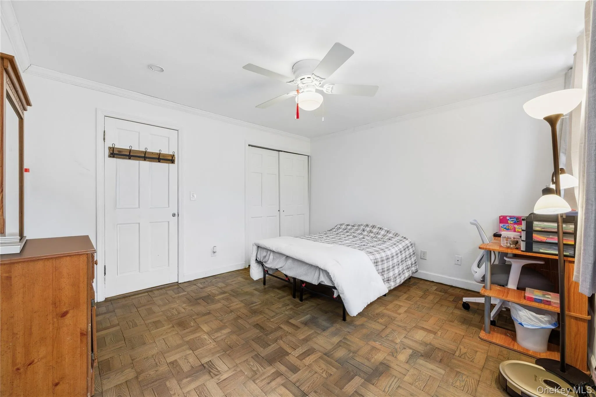 Bedroom with parquet floors, ornamental molding, a ceiling fan, and a closet Bedroom with parquet floors, ornamental molding, a ceiling fan, and a closet