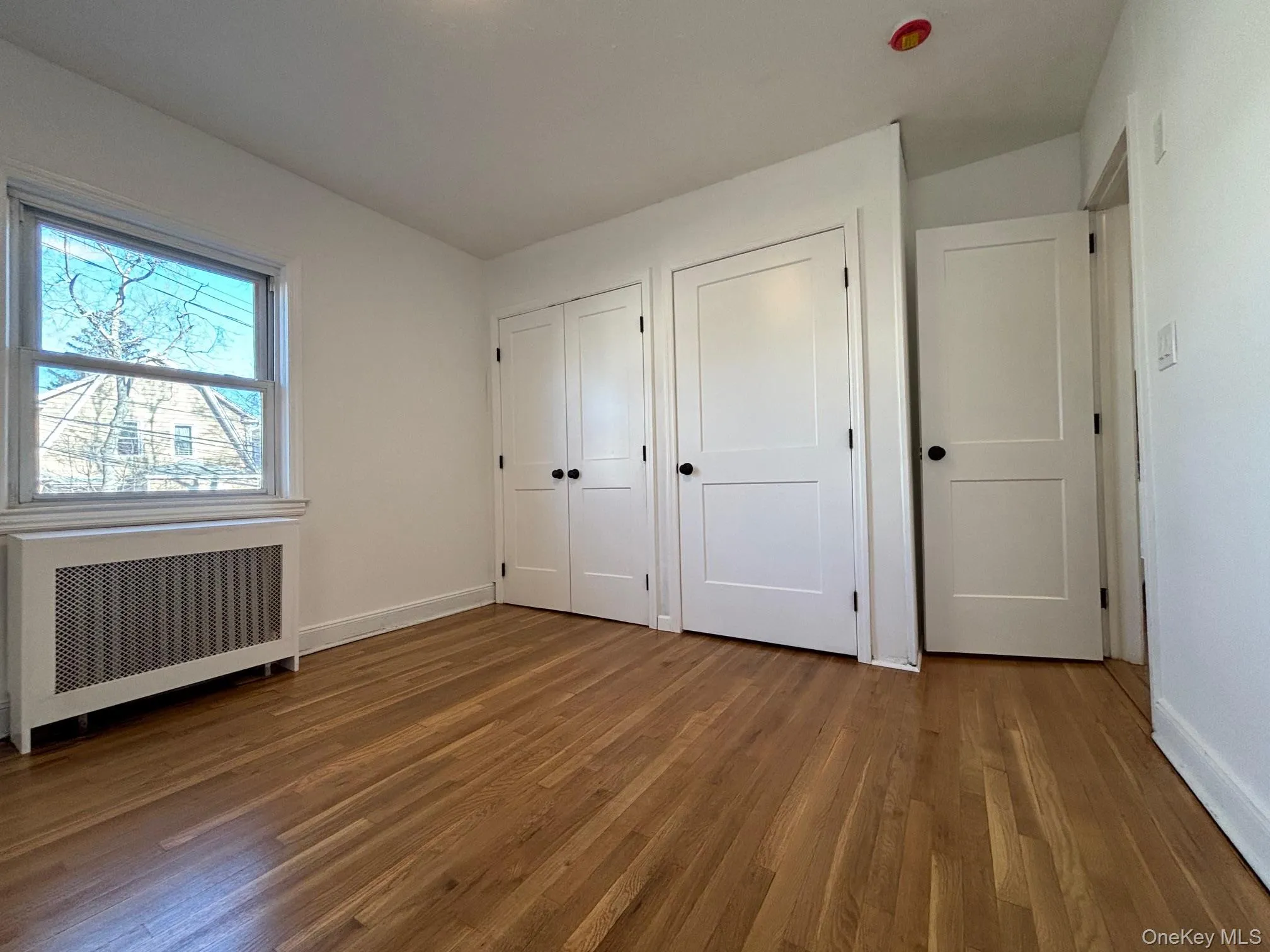 Primary bedroom with ample closet space and refinished wood floor. Primary bedroom with ample closet space and refinished wood floor.
