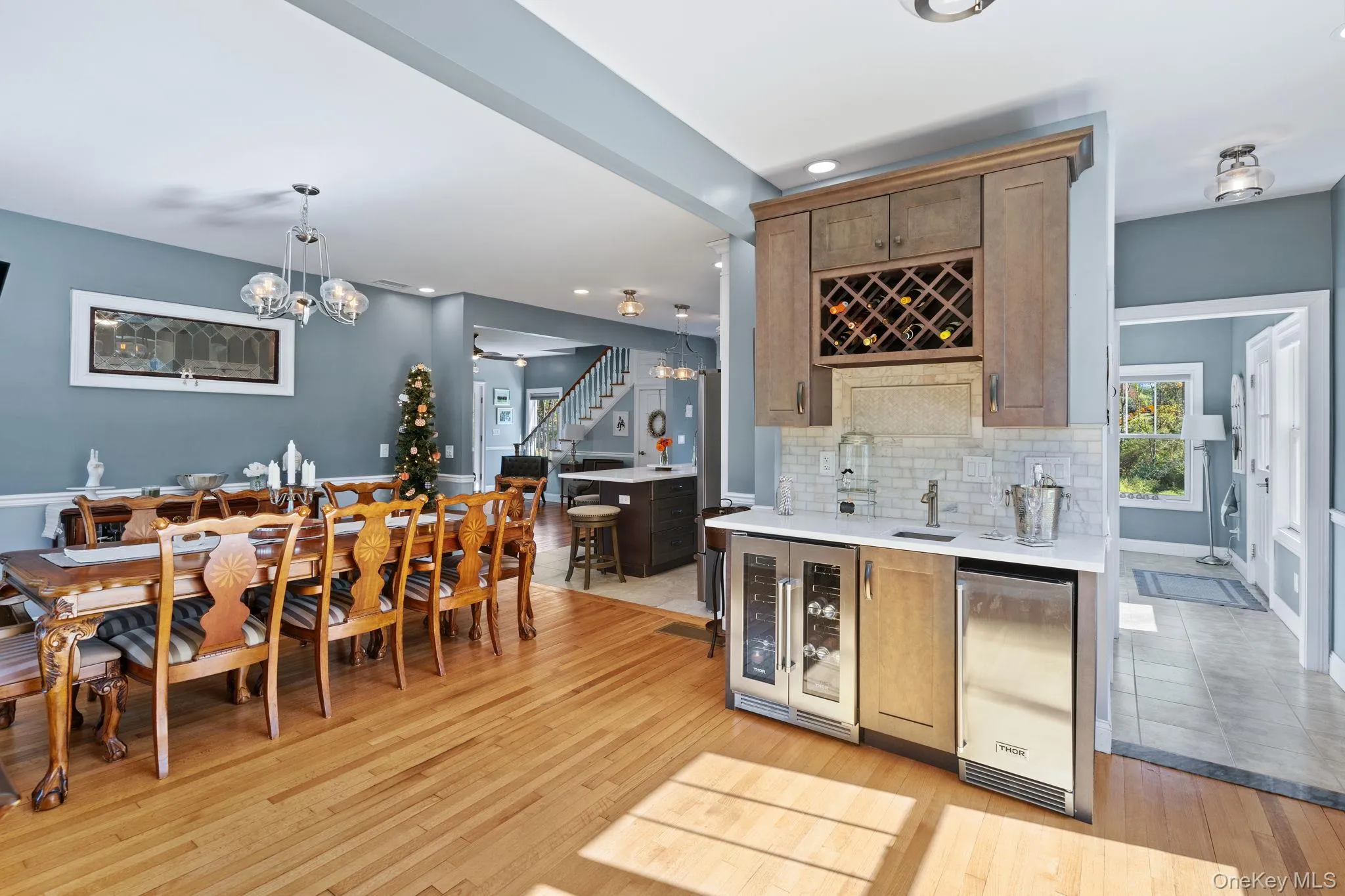Indoor wet bar featuring stairs, hanging light fixtures, wine cooler, recessed lighting, and healthy amount of natural light Indoor wet bar featuring stairs, hanging light fixtures, wine cooler, recessed lighting, and healthy amount of natural light