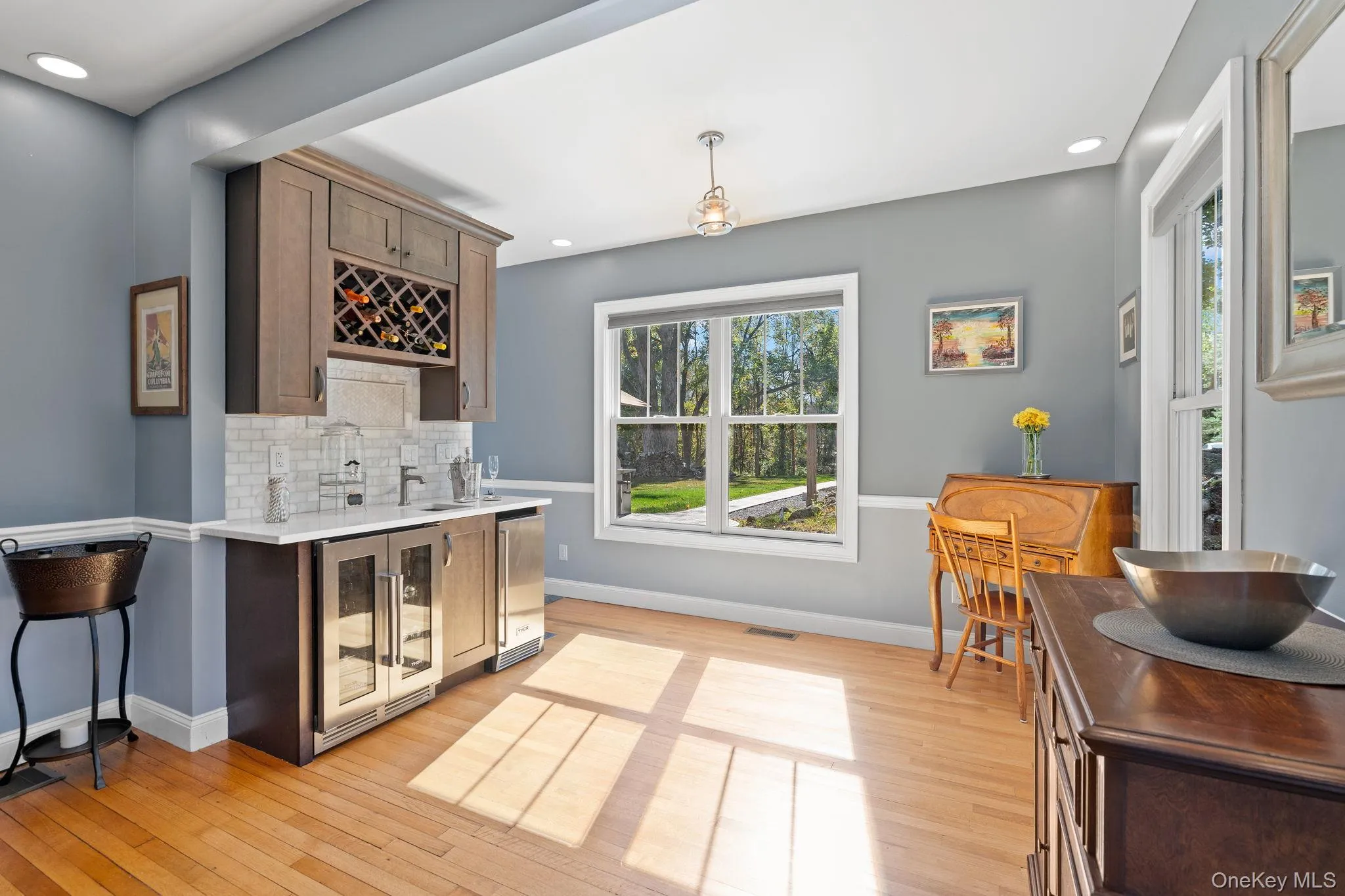 Indoor wet bar with wine cooler, tasteful backsplash, light wood-style flooring, light stone countertops, and recessed lighting Indoor wet bar with wine cooler, tasteful backsplash, light wood-style flooring, light stone countertops, and recessed lighting
