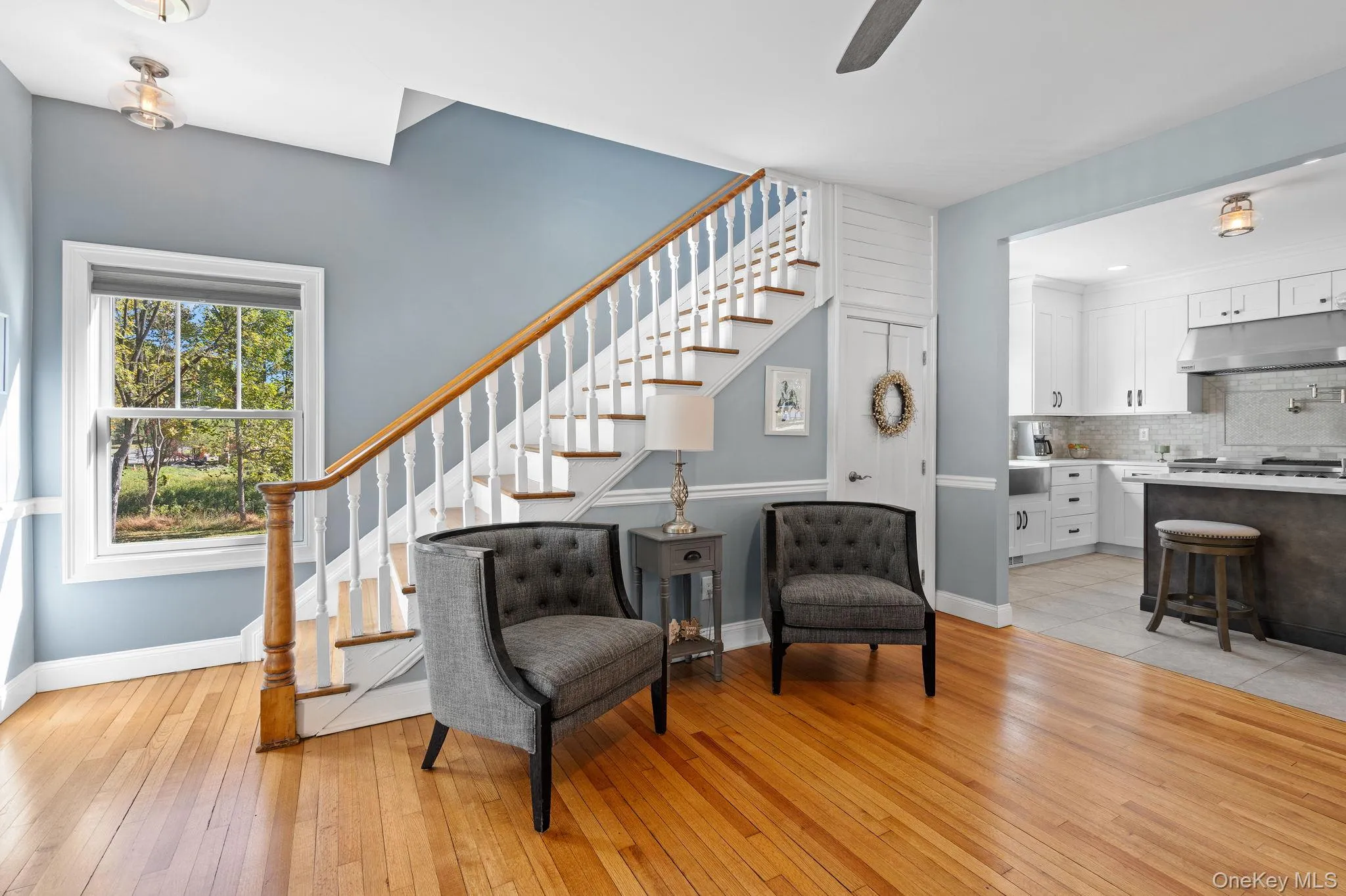 Sitting room featuring stairway, light wood-style flooring, and a ceiling fan Sitting room featuring stairway, light wood-style flooring, and a ceiling fan