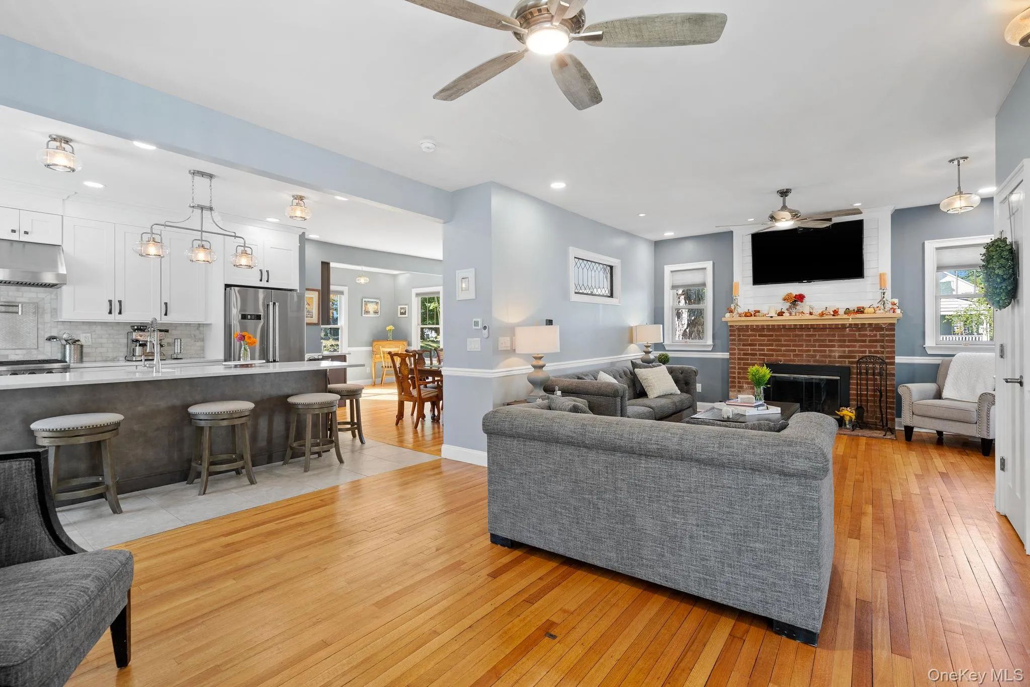 Living area featuring light wood-type flooring, a fireplace, recessed lighting, and a ceiling fan Living area featuring light wood-type flooring, a fireplace, recessed lighting, and a ceiling fan