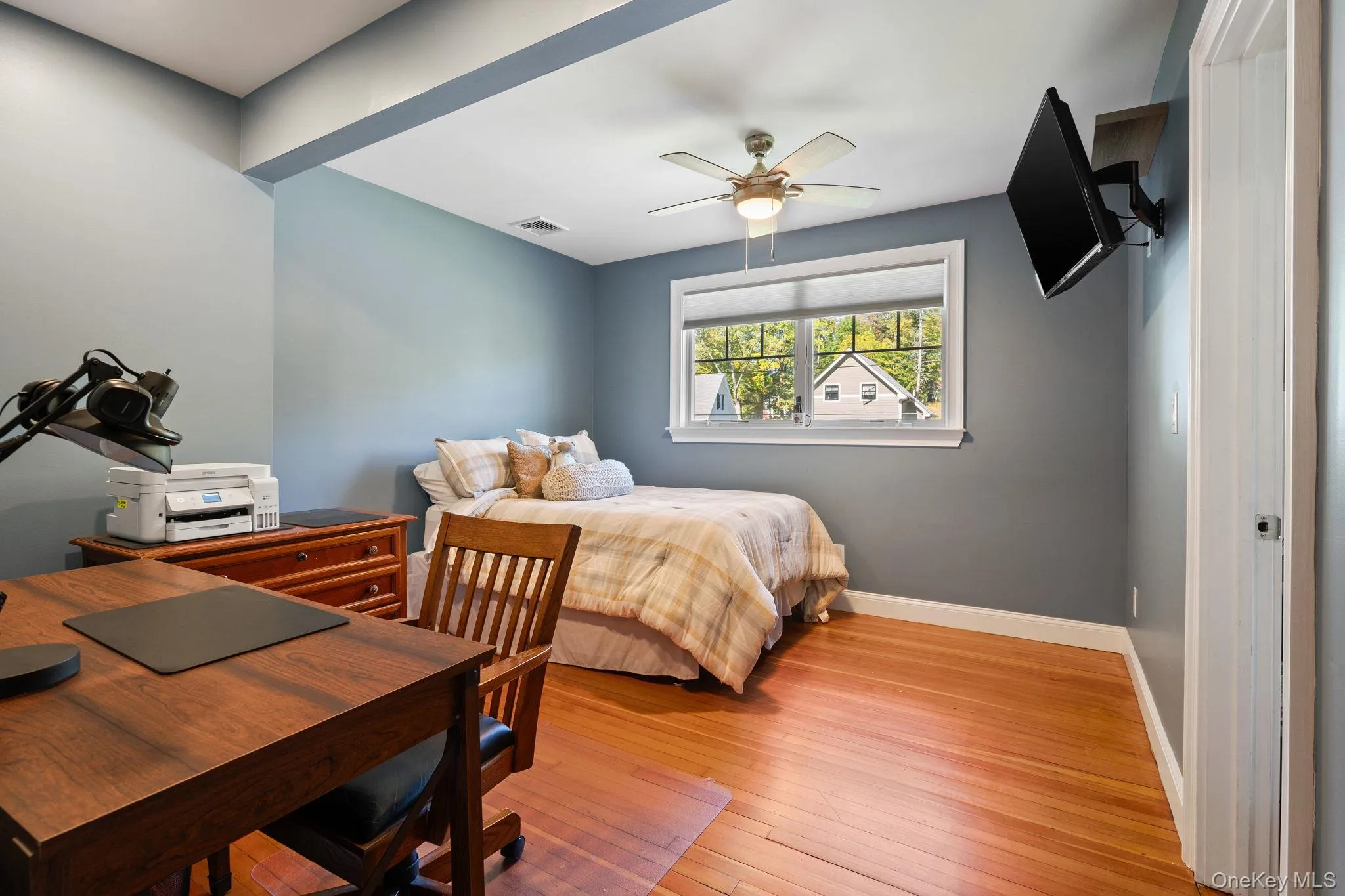 Bedroom with light wood-style flooring, an office area, and a ceiling fan Bedroom with light wood-style flooring, an office area, and a ceiling fan