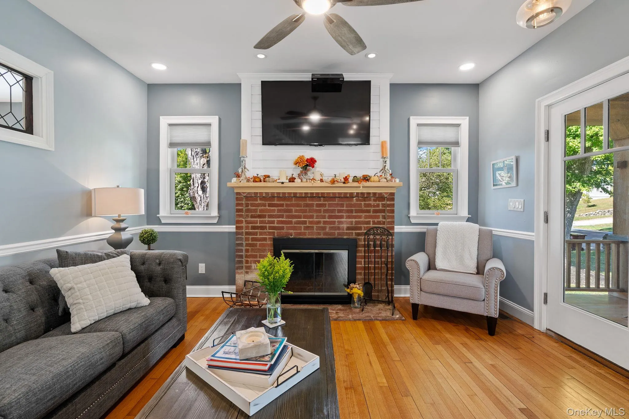 Living area featuring hardwood / wood-style flooring, a brick fireplace, recessed lighting, and a ceiling fan Living area featuring hardwood / wood-style flooring, a brick fireplace, recessed lighting, and a ceiling fan
