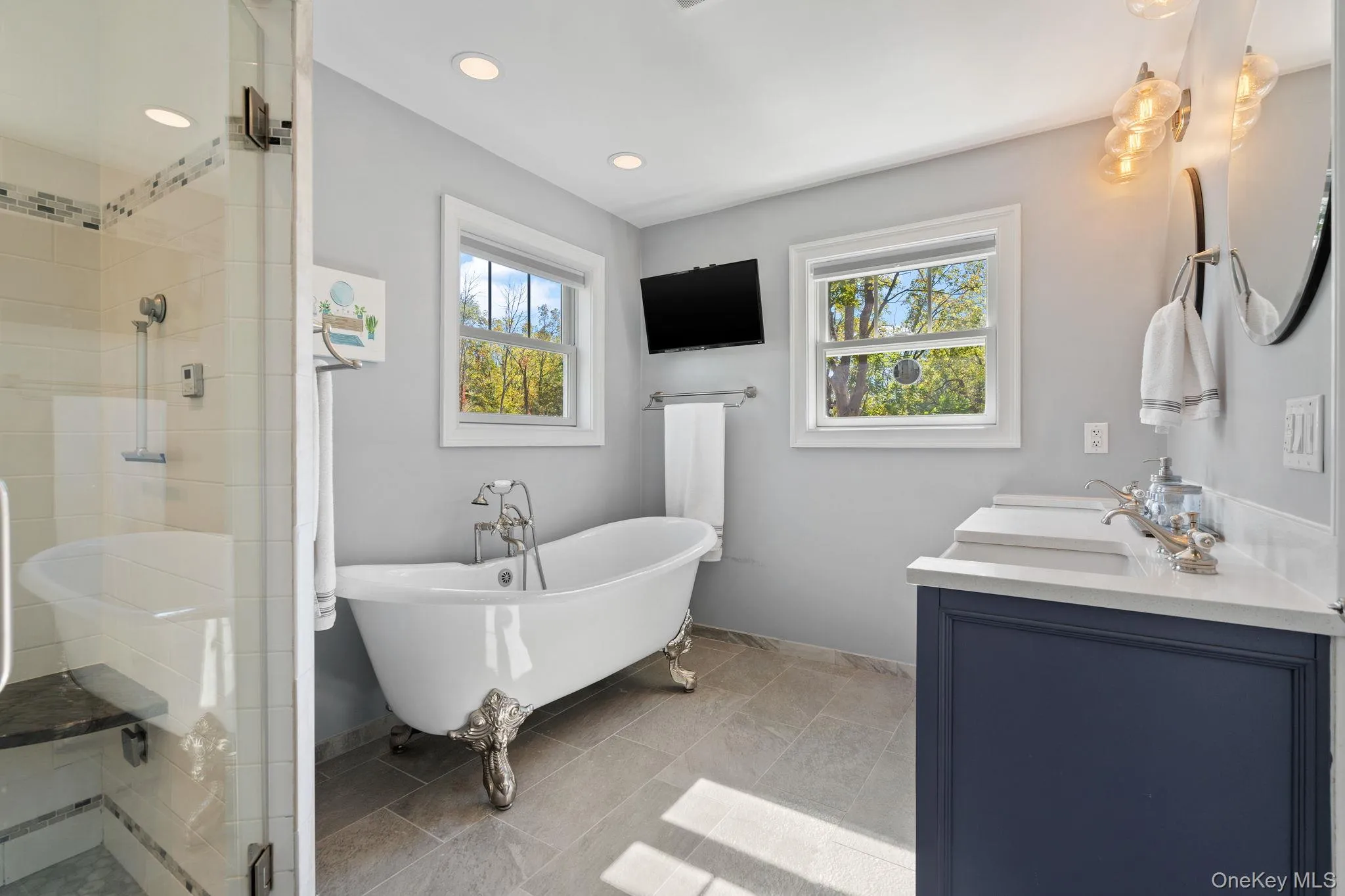Full bathroom with healthy amount of natural light, double vanity, a freestanding tub, a shower stall, and recessed lighting Full bathroom with healthy amount of natural light, double vanity, a freestanding tub, a shower stall, and recessed lighting