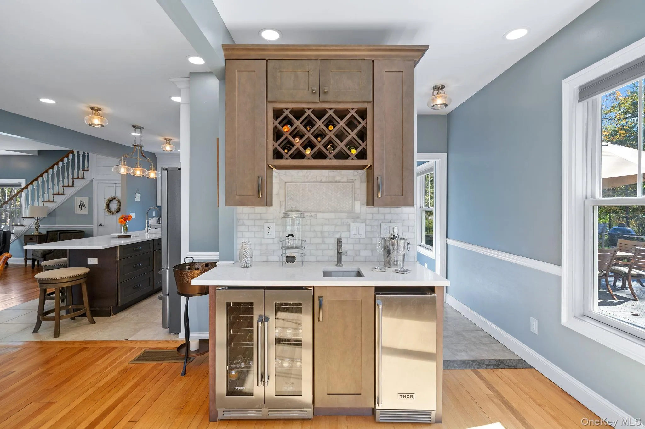 Indoor wet bar featuring beverage cooler, recessed lighting, light wood-style floors, light stone countertops, and stairway Indoor wet bar featuring beverage cooler, recessed lighting, light wood-style floors, light stone countertops, and stairway