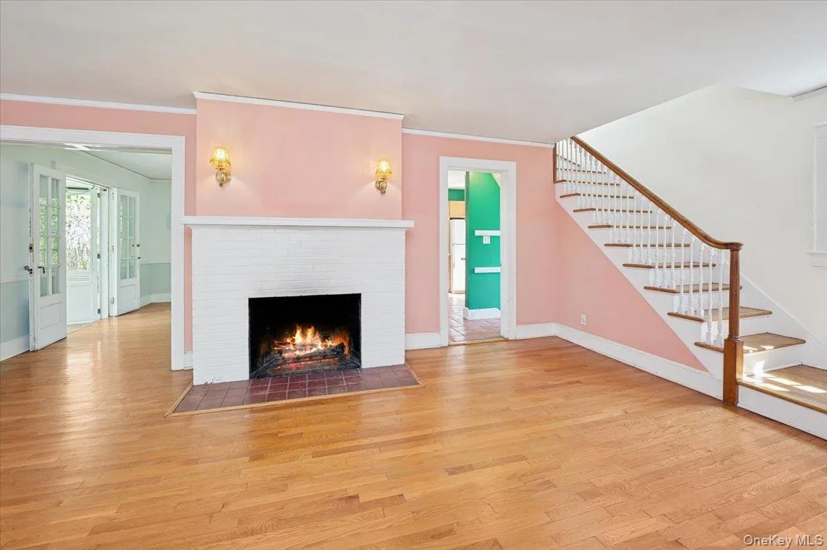 Living room with hardwood floors, wood burning fireplace and mantle with stairs to the second floor Living room with hardwood floors, wood burning fireplace and mantle with stairs to the second floor
