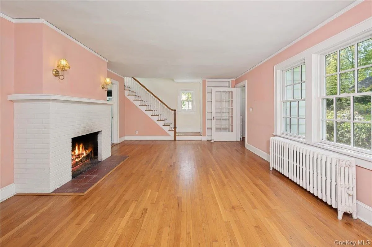 Living room with hardwood floors, wood burning fireplace and mantle with stairs to the second floor Living room with hardwood floors, wood burning fireplace and mantle with stairs to the second floor