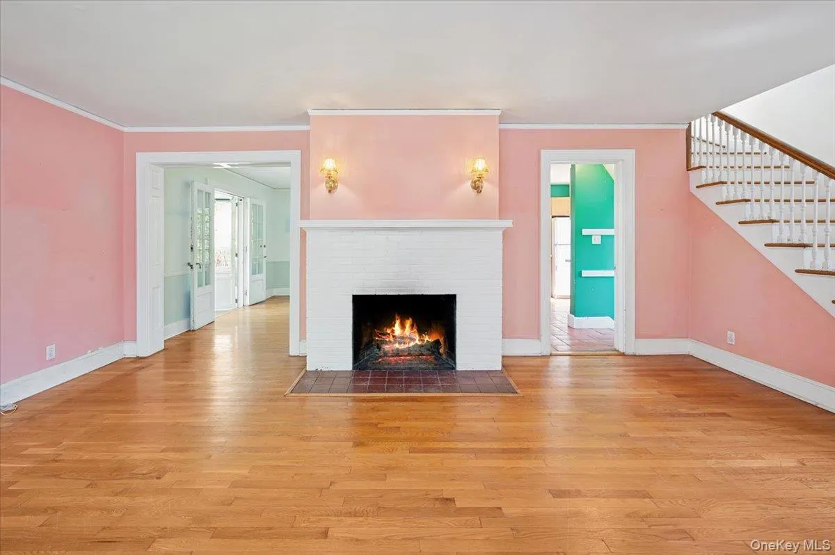 Living room with hardwood floors, wood burning fireplace and mantle with stairs to the second floor Living room with hardwood floors, wood burning fireplace and mantle with stairs to the second floor