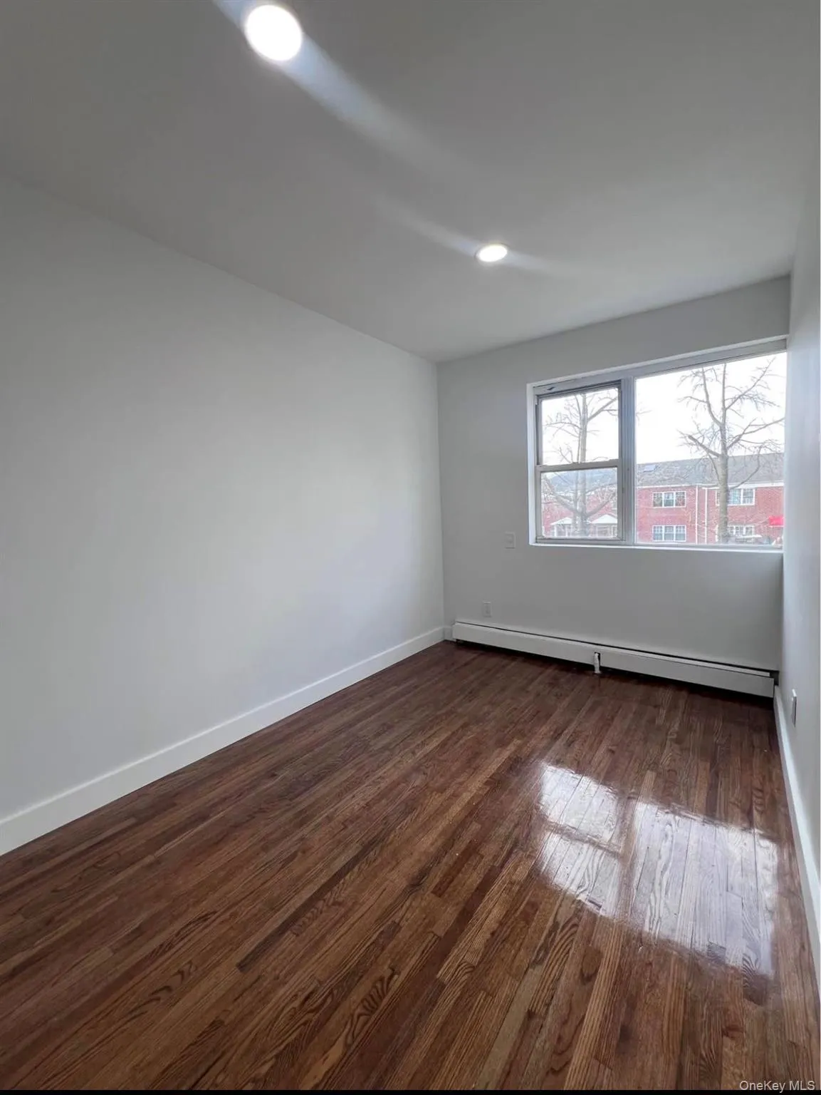 Empty room featuring dark wood-style flooring, a baseboard heating unit, and recessed lighting Empty room featuring dark wood-style flooring, a baseboard heating unit, and recessed lighting