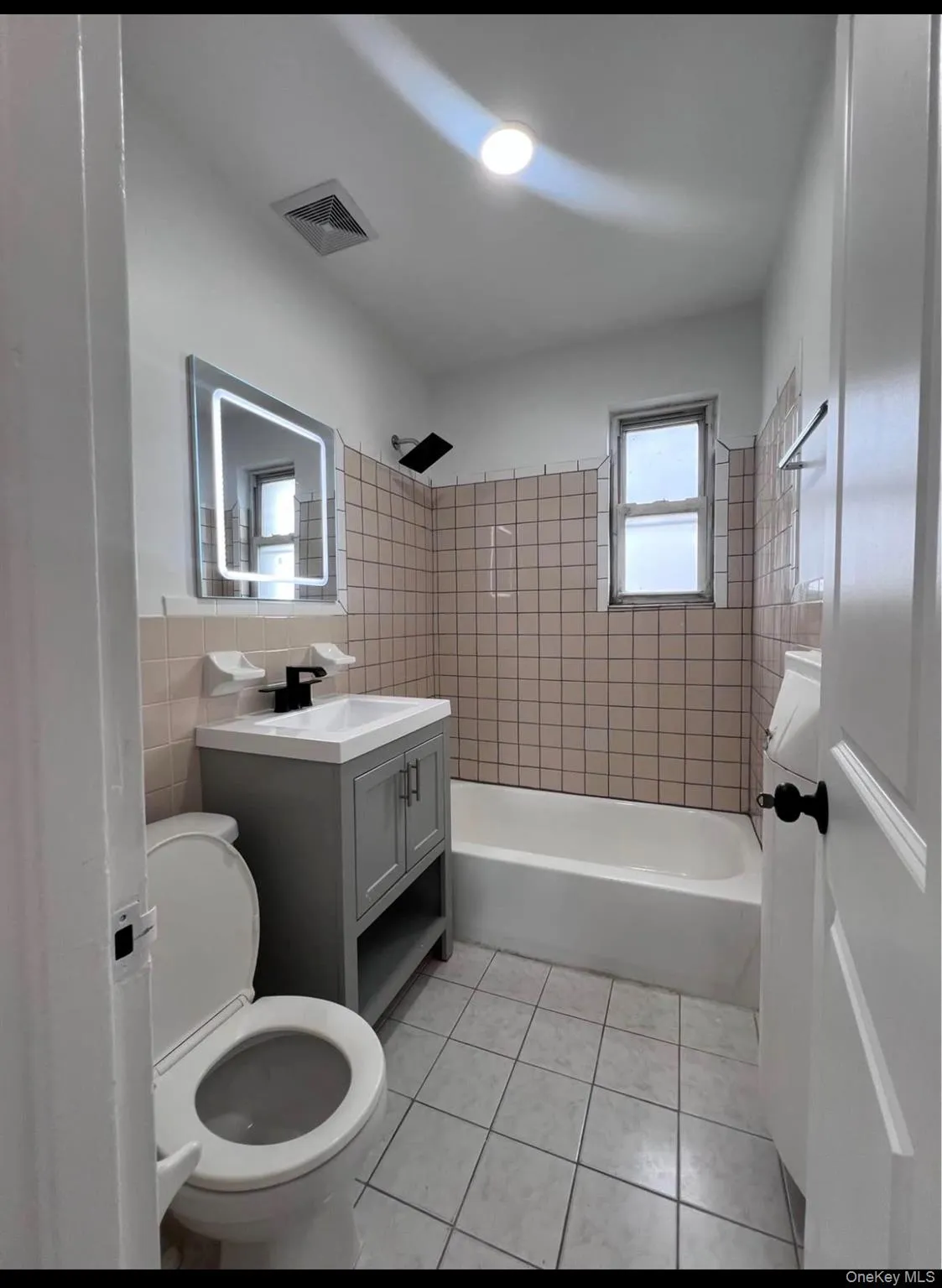 Full bathroom featuring vanity, shower combination, light tile patterned floors, and tile walls Full bathroom featuring vanity, shower combination, light tile patterned floors, and tile walls