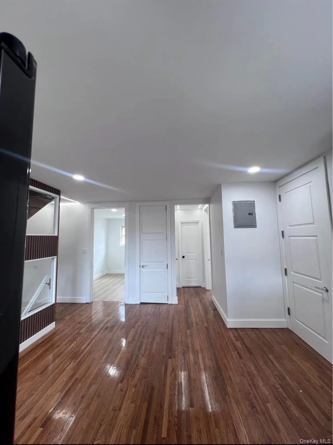 Unfurnished living room with dark wood-style flooring and electric panel Unfurnished living room with dark wood-style flooring and electric panel