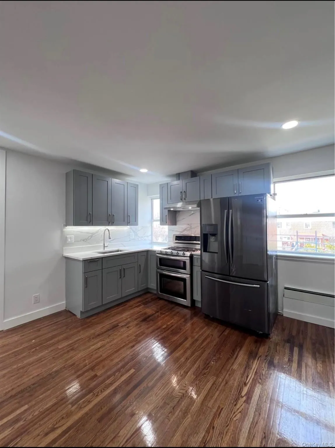 Kitchen featuring black fridge, gray cabinetry, double oven range, and dark wood-type flooring Kitchen featuring black fridge, gray cabinetry, double oven range, and dark wood-type flooring